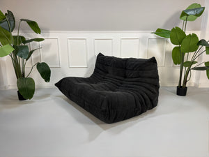 Gebrauchtes graues Ligne Roset Togo Designer Stoff Sofa vor einer Wand, stilvoll und modern eingerichtet.