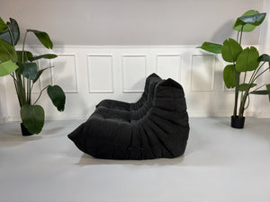 Gebrauchtes graues Ligne Roset Togo Designer Stoff Sofa vor einer Wand, stilvoll und modern eingerichtet.