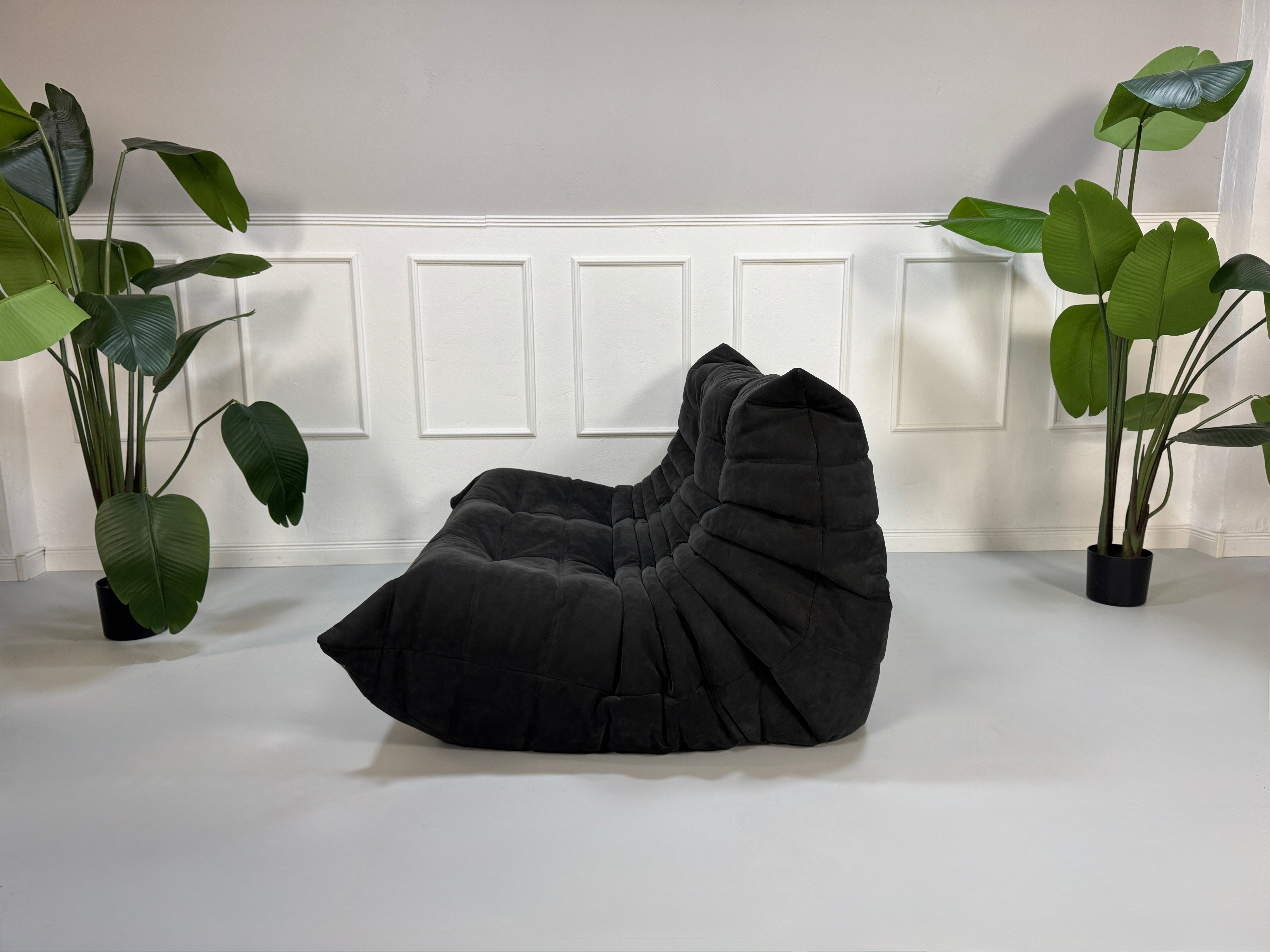 Gebrauchtes graues Ligne Roset Togo Designer Stoff Sofa vor einer Wand, stilvoll und modern eingerichtet.