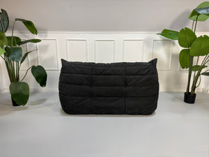 Gebrauchtes graues Ligne Roset Togo Designer Stoff Sofa vor einer Wand, stilvoll und modern eingerichtet.