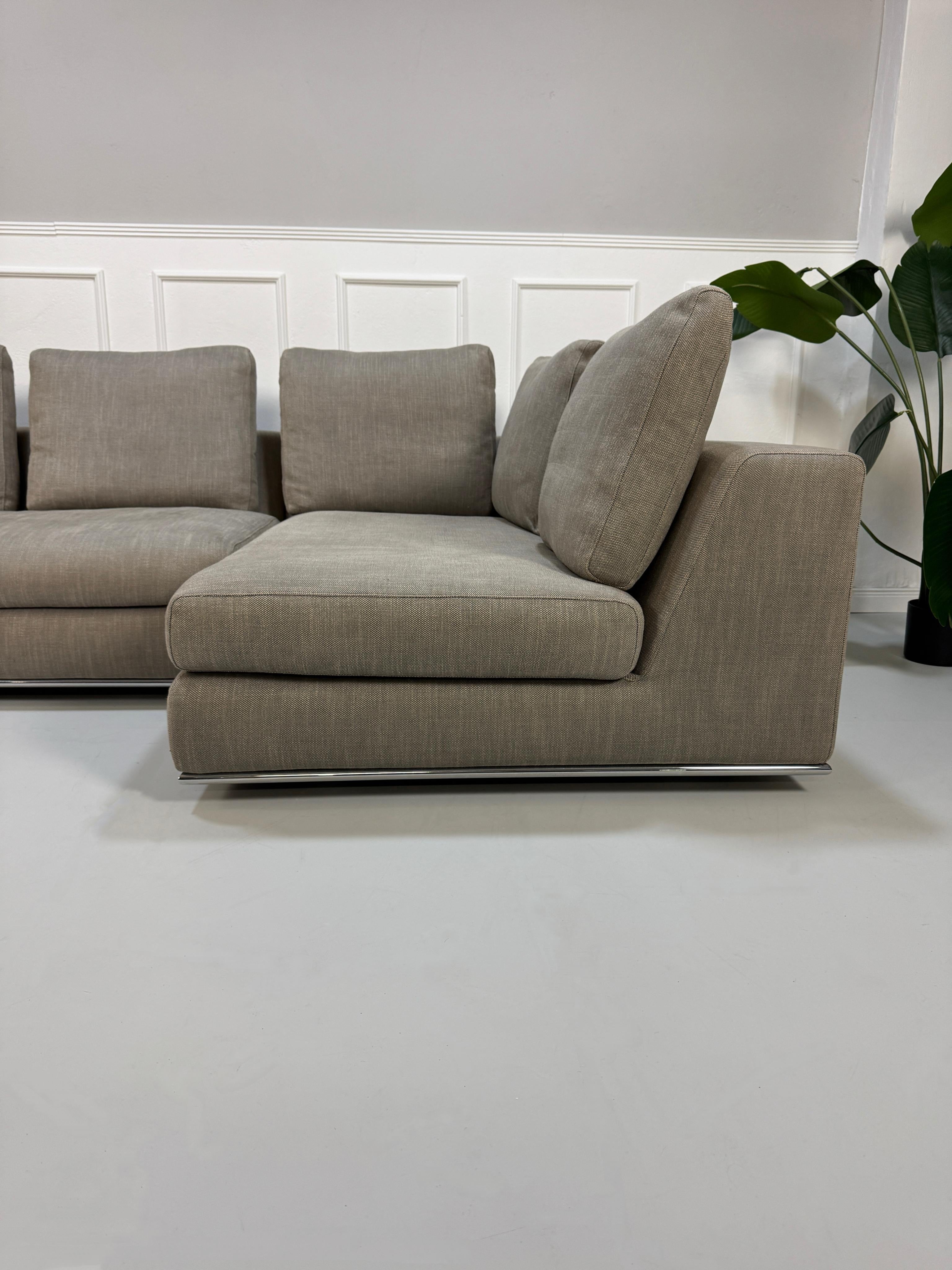 Gebrauchtes graues Minotti Hamilton Designer Stoff Sofa vor einer Wand, stilvoll und modern eingerichtet.