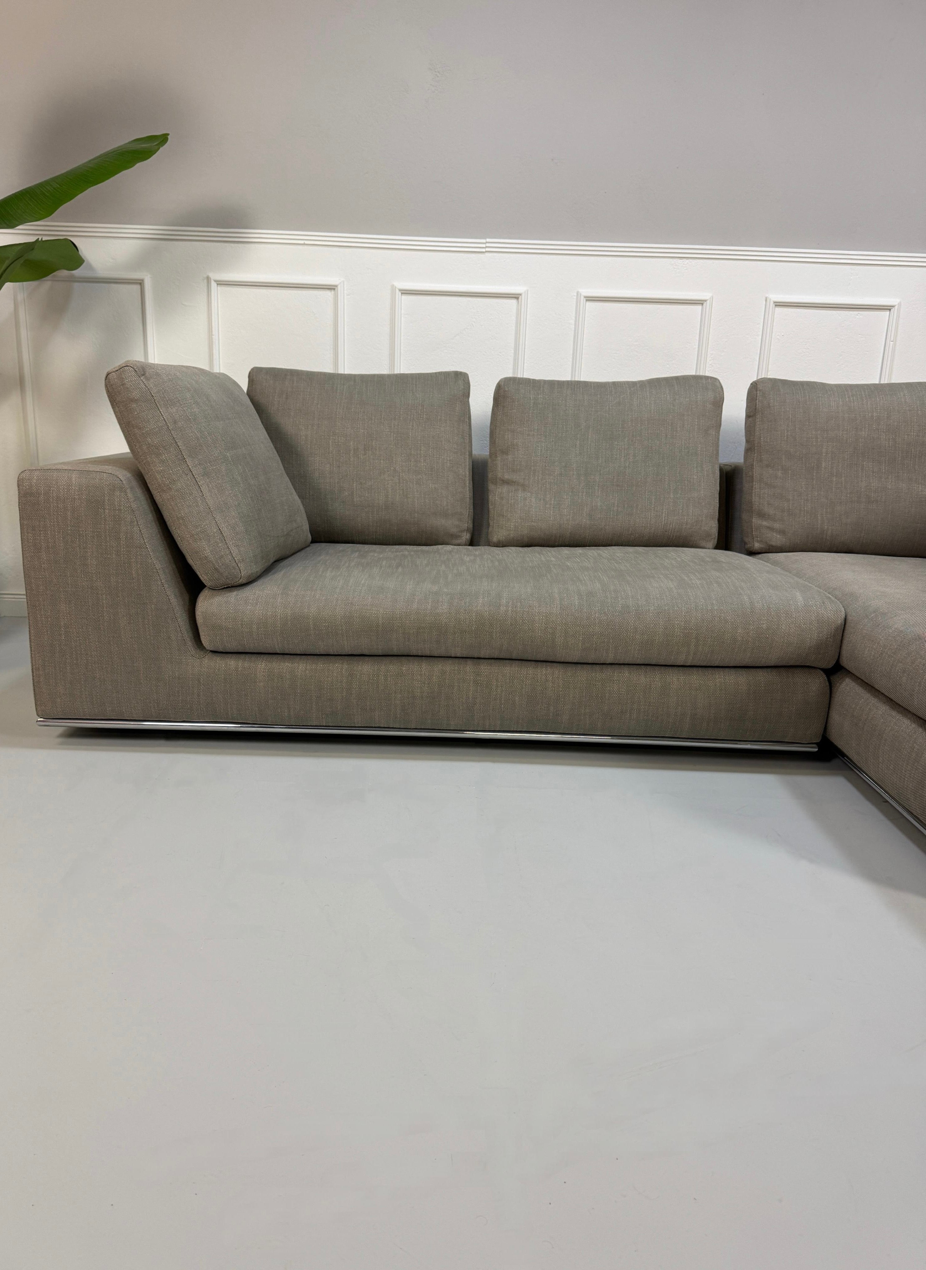 Gebrauchtes graues Minotti Hamilton Designer Stoff Sofa vor einer Wand, stilvoll und modern eingerichtet.