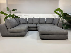 Gebrauchtes graues Minotti Hamilton Designer Stoff Sofa mit einem Hocker vor einer Wand, stilvoll und modern eingerichtet.