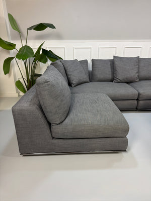 Gebrauchtes graues Minotti Hamilton Designer Stoff Sofa mit einem Hocker vor einer Wand, stilvoll und modern eingerichtet.