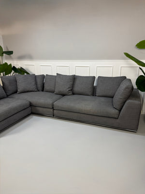 Gebrauchtes graues Minotti Hamilton Designer Stoff Sofa mit einem Hocker vor einer Wand, stilvoll und modern eingerichtet.
