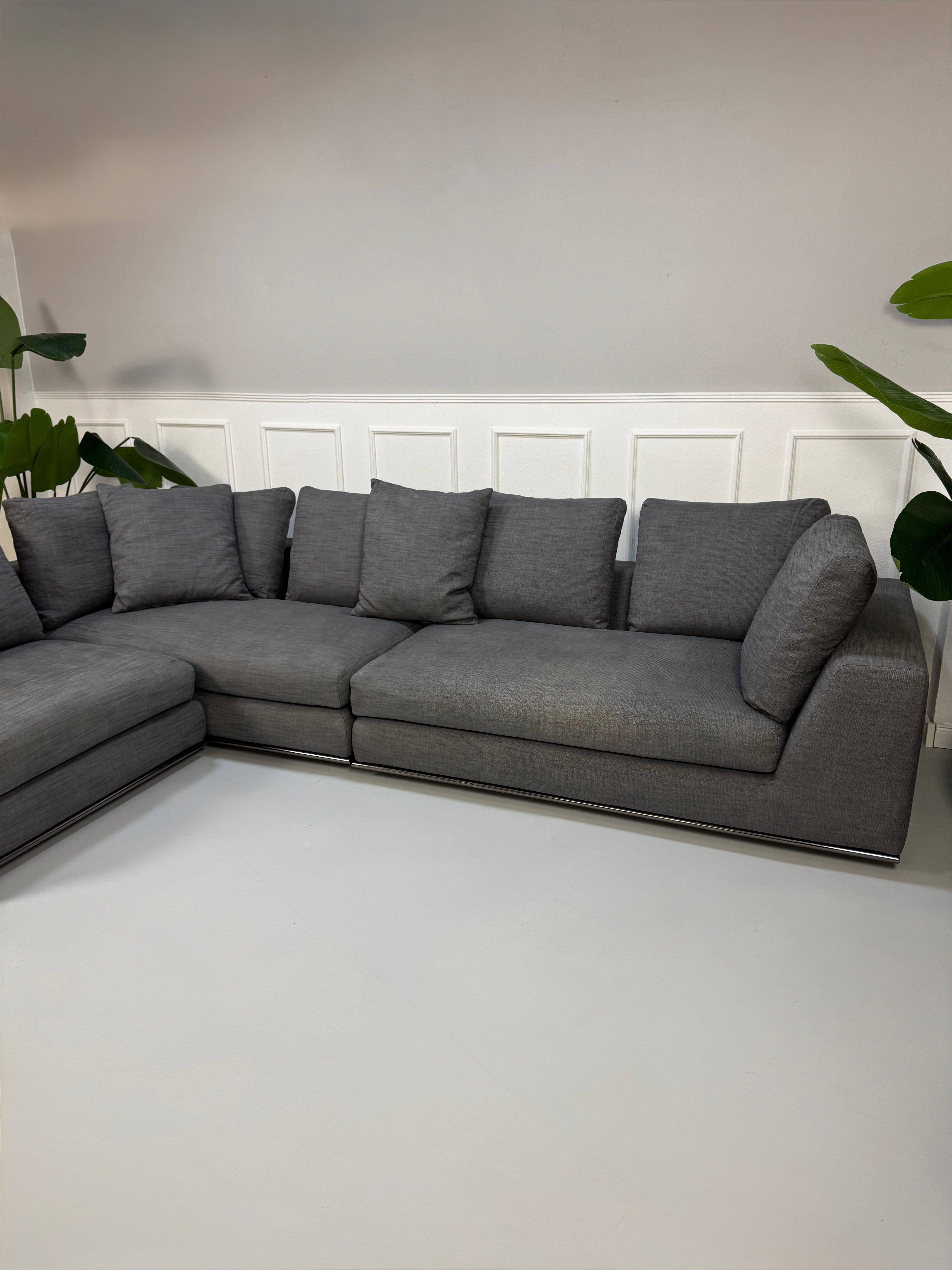 Gebrauchtes graues Minotti Hamilton Designer Stoff Sofa mit einem Hocker vor einer Wand, stilvoll und modern eingerichtet.