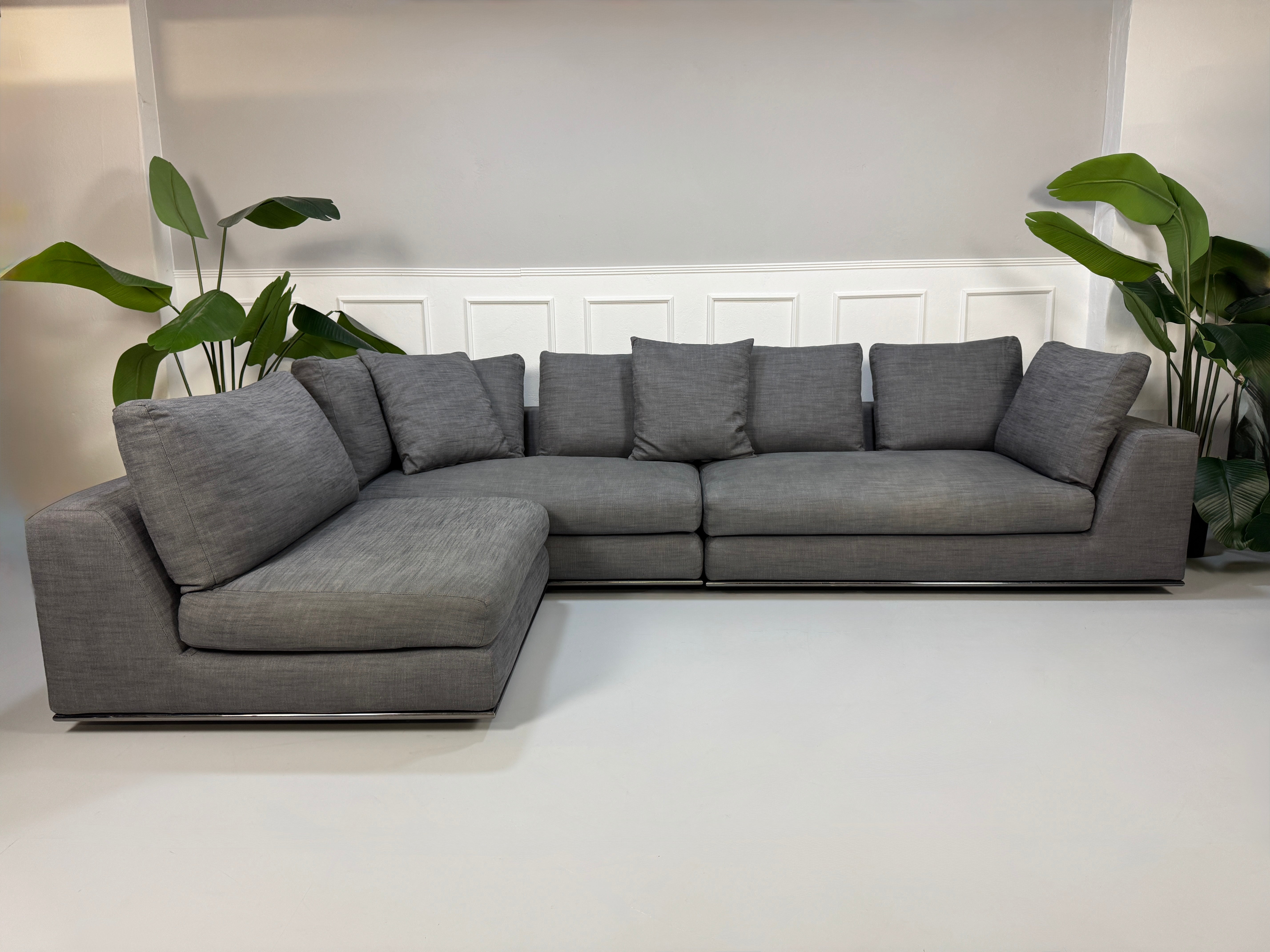Gebrauchtes graues Minotti Hamilton Designer Stoff Sofa mit einem Hocker vor einer Wand, stilvoll und modern eingerichtet.