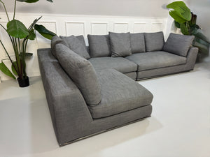 Gebrauchtes graues Minotti Hamilton Designer Stoff Sofa mit einem Hocker vor einer Wand, stilvoll und modern eingerichtet.