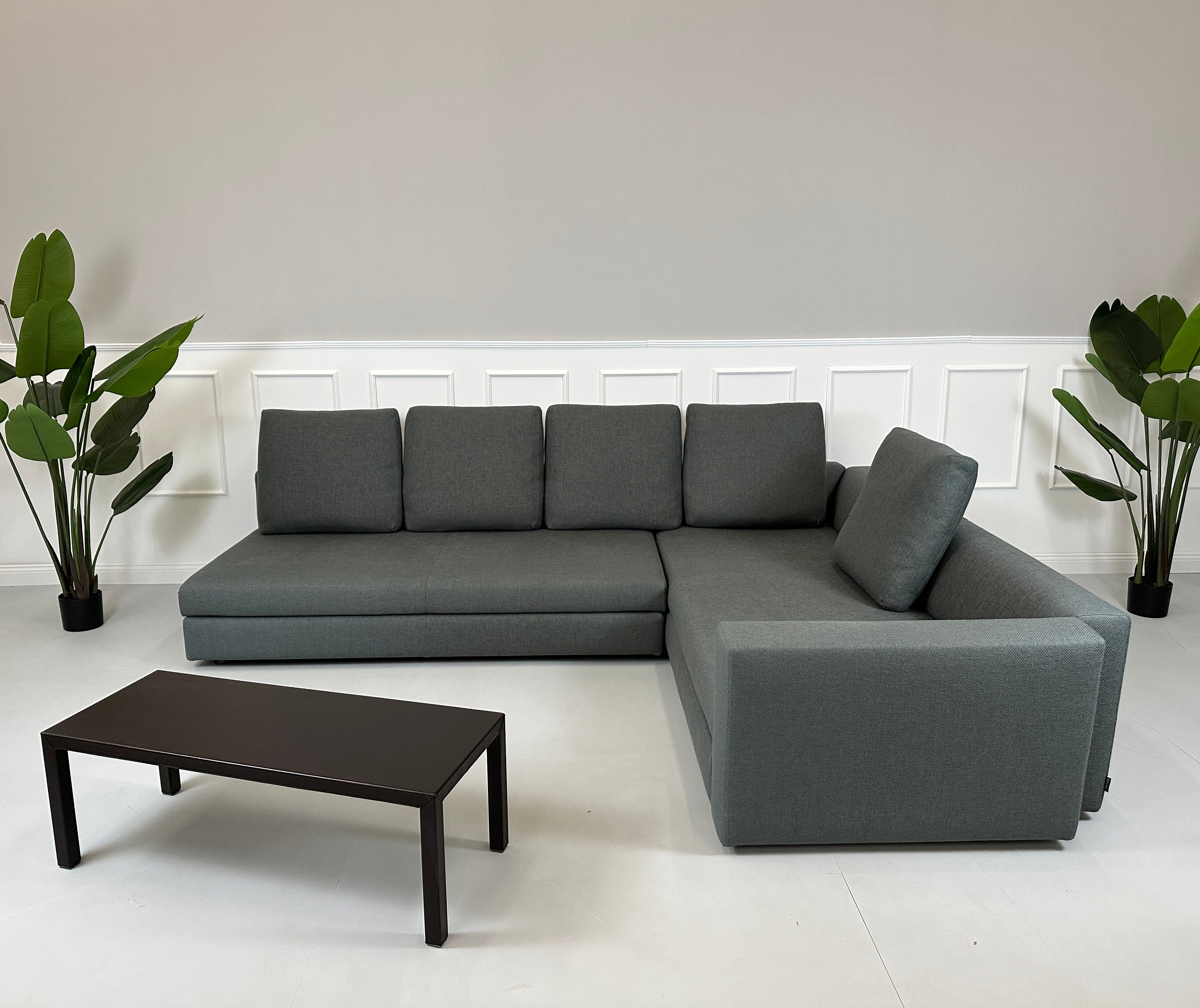 Gebrauchtes grünes Minotti Kline Designer Stoff Sofa vor einer Wand, stilvoll und modern eingerichtet mit Tisch.