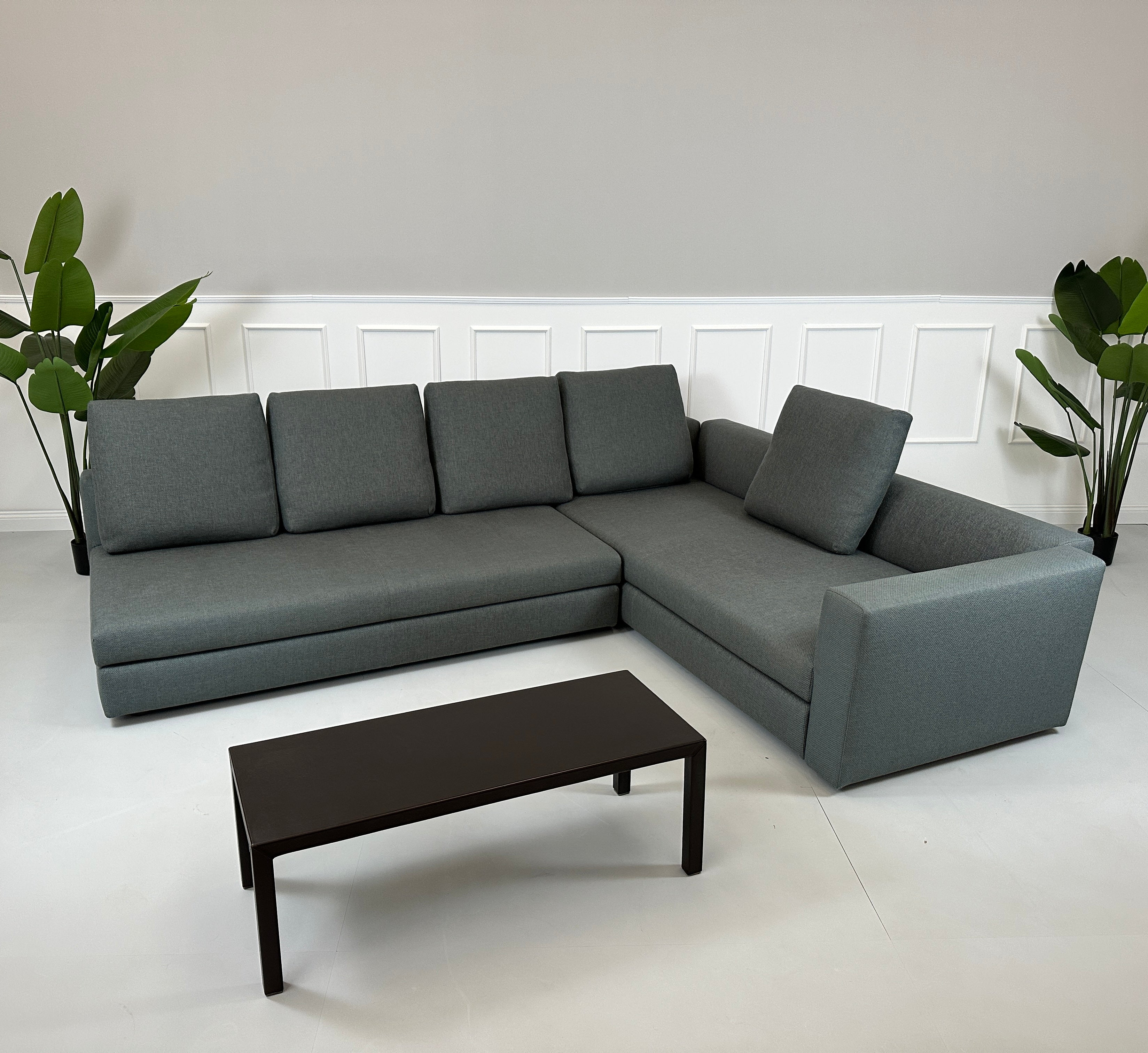 Gebrauchtes grünes Minotti Kline Designer Stoff Sofa vor einer Wand, stilvoll und modern eingerichtet mit Tisch.