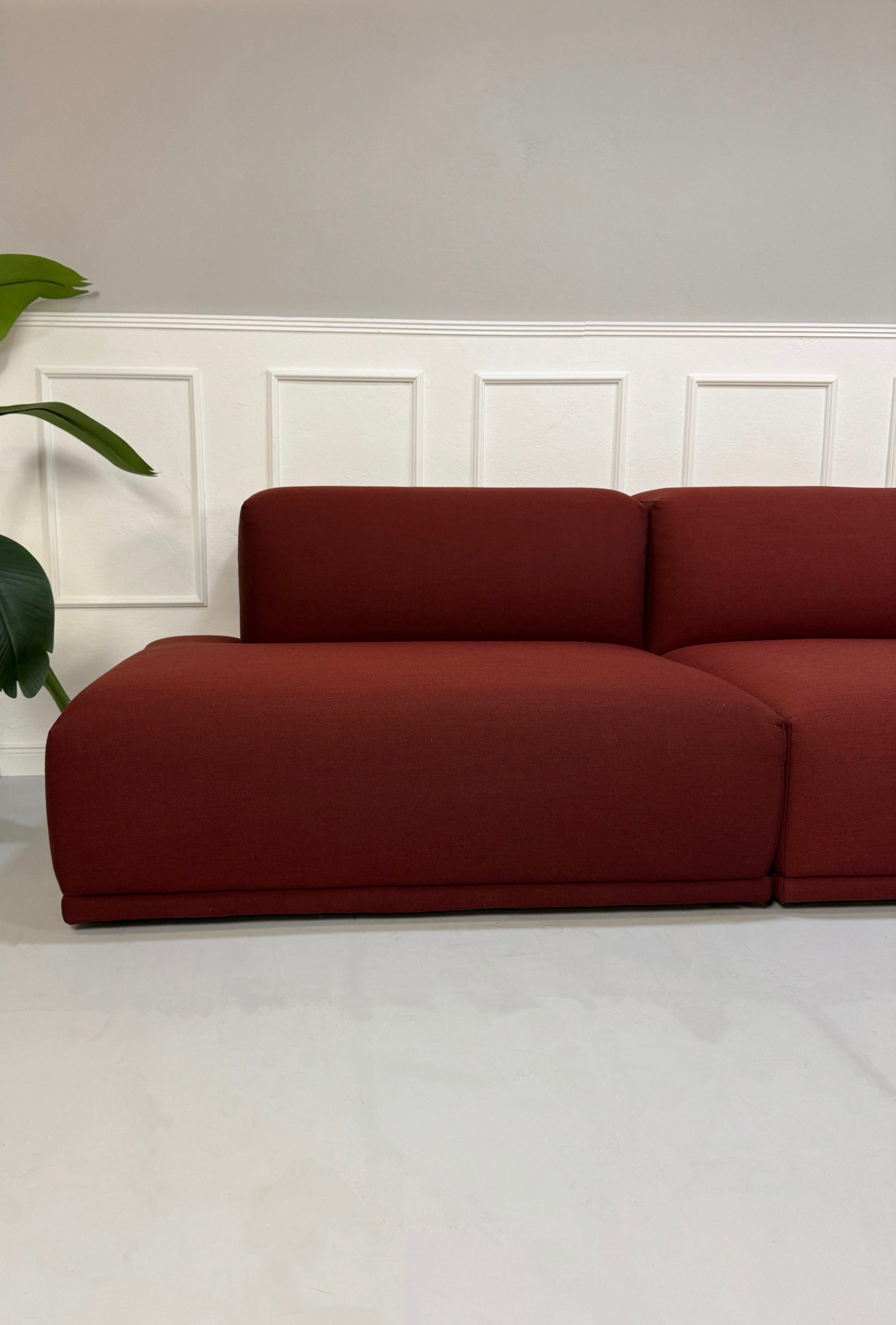 Gebrauchtes rotes Muuto Connect  Designer Stoff Sofa vor einer Wand, stilvoll und modern eingerichtet.