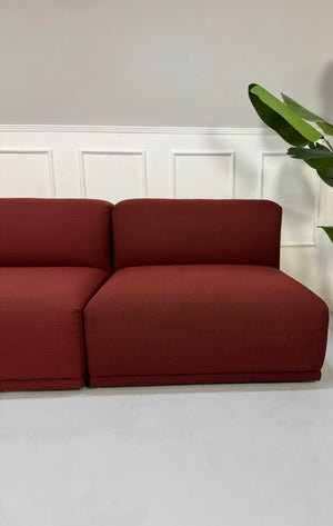 Gebrauchtes rotes Muuto Connect  Designer Stoff Sofa vor einer Wand, stilvoll und modern eingerichtet.