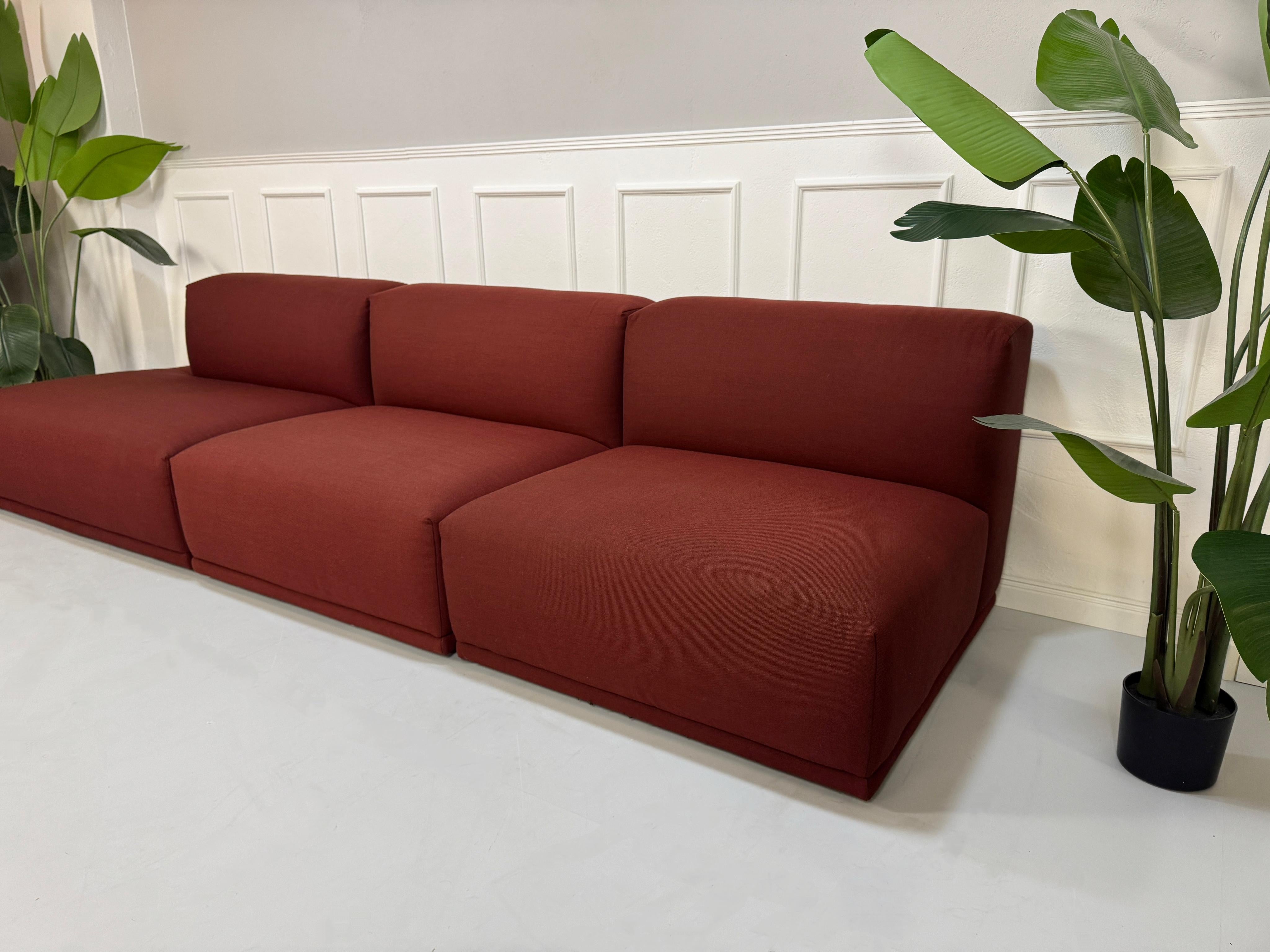 Gebrauchtes rotes Muuto Connect  Designer Stoff Sofa vor einer Wand, stilvoll und modern eingerichtet.