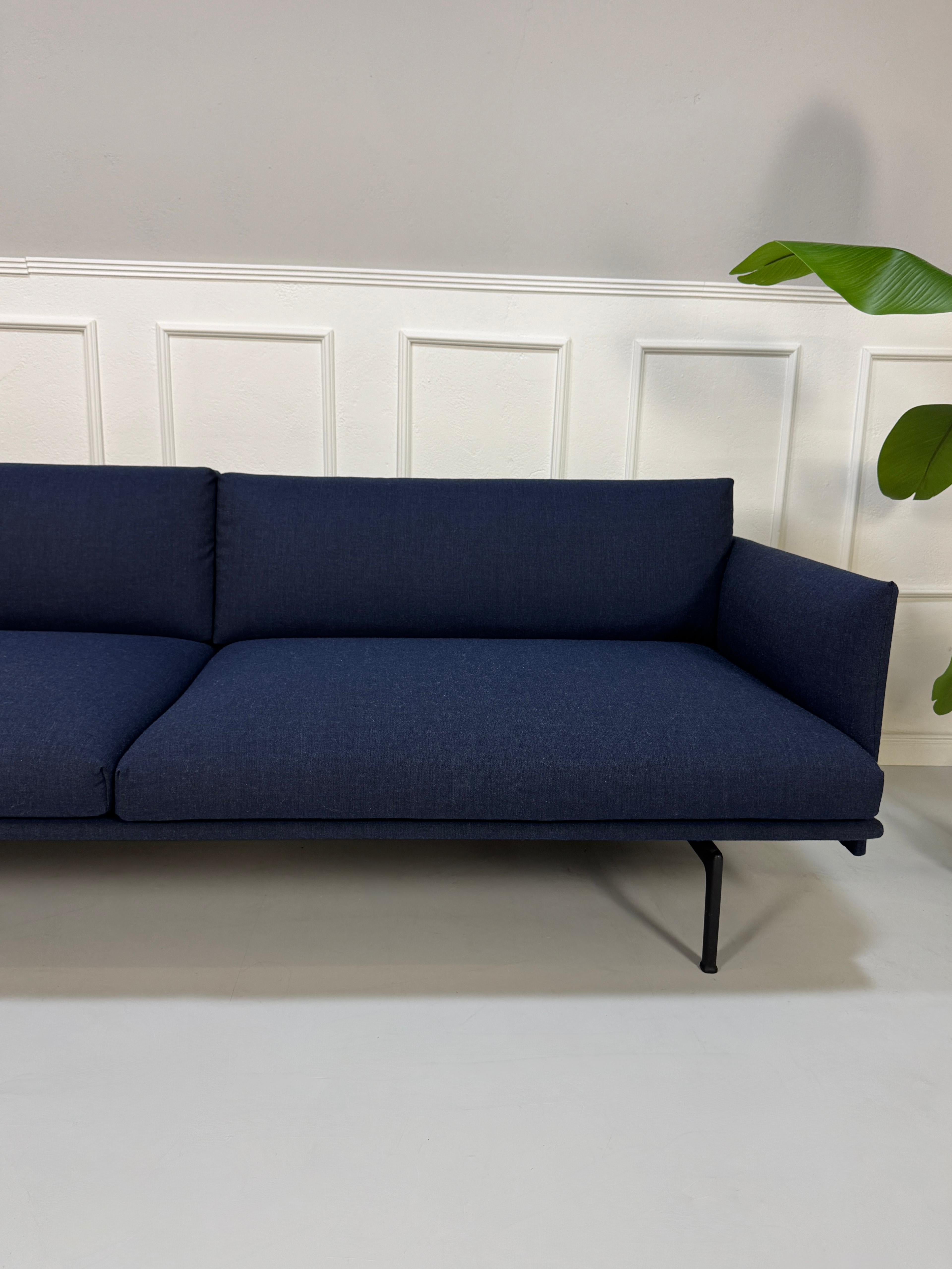 Gebrauchtes blaues Muuto Outline Designer Stoff Sofa vor einer Wand, stilvoll und modern eingerichtet.