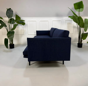 Gebrauchtes blaues Muuto Outline Designer Stoff Sofa vor einer Wand, stilvoll und modern eingerichtet.