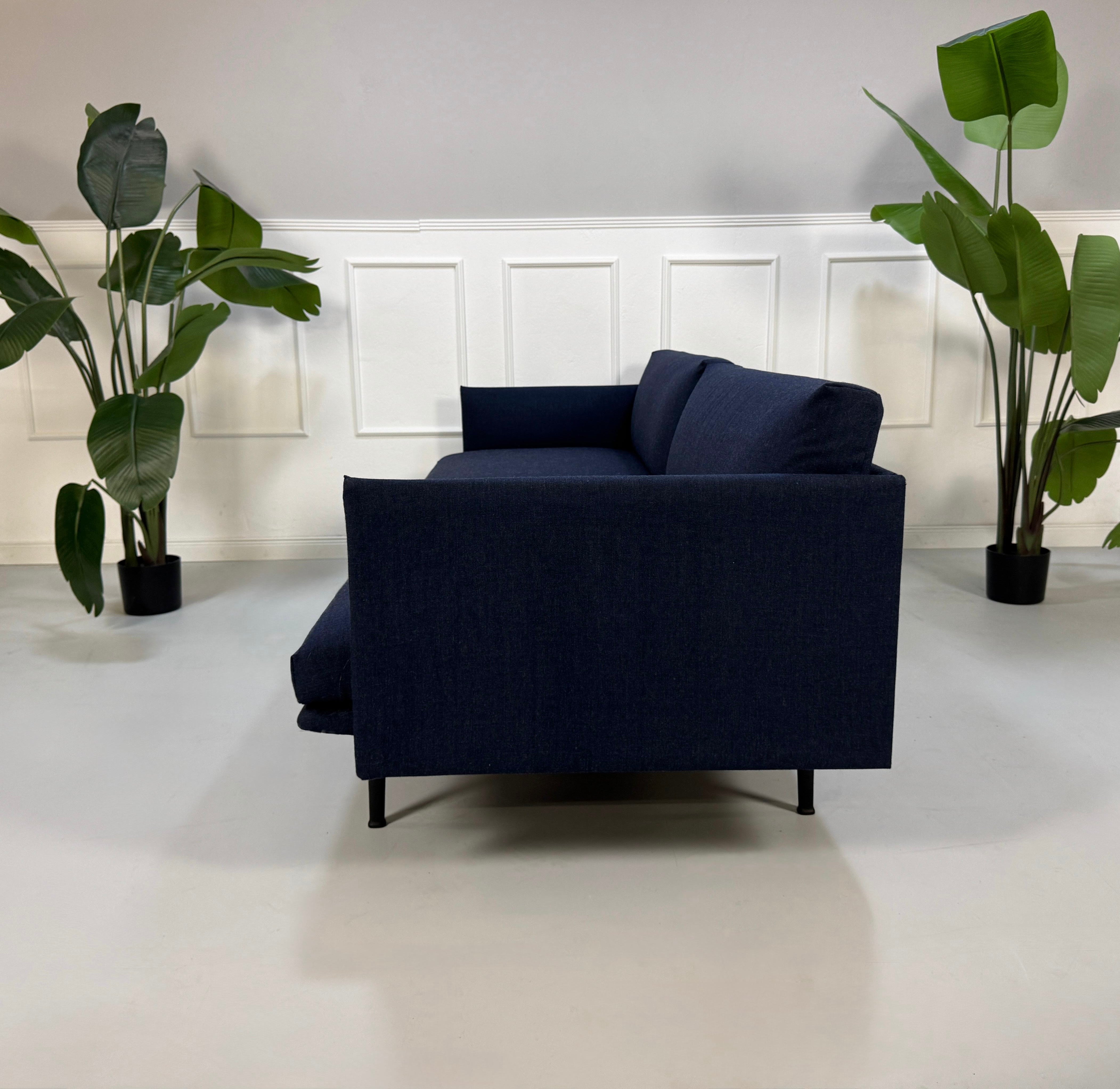 Gebrauchtes blaues Muuto Outline Designer Stoff Sofa vor einer Wand, stilvoll und modern eingerichtet.