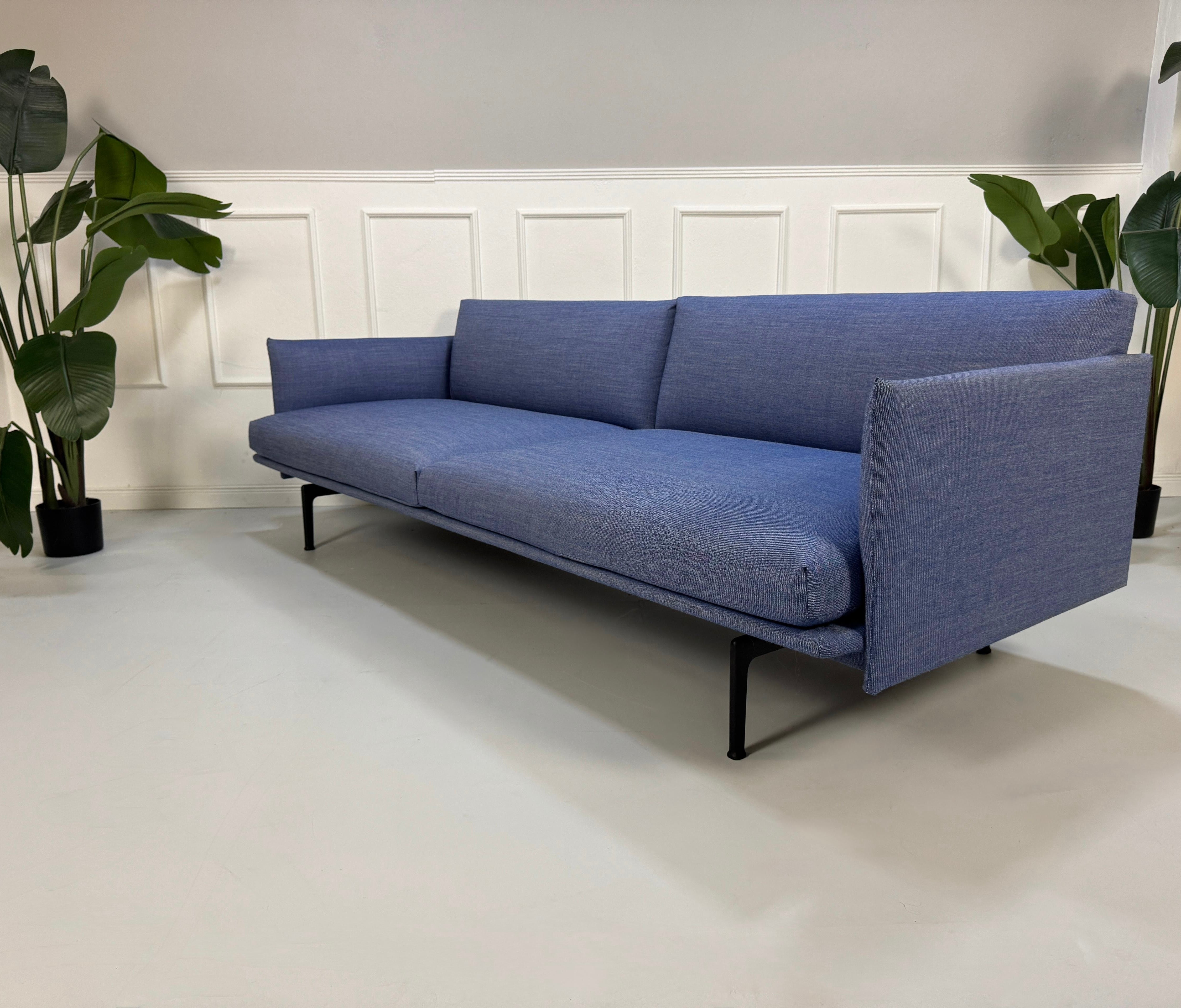 Gebrauchtes blaues Muuto Outline Designer Stoff Sofa vor einer Wand, stilvoll und modern eingerichtet.