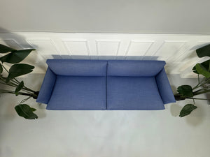 Gebrauchtes blaues Muuto Outline Designer Stoff Sofa vor einer Wand, stilvoll und modern eingerichtet.