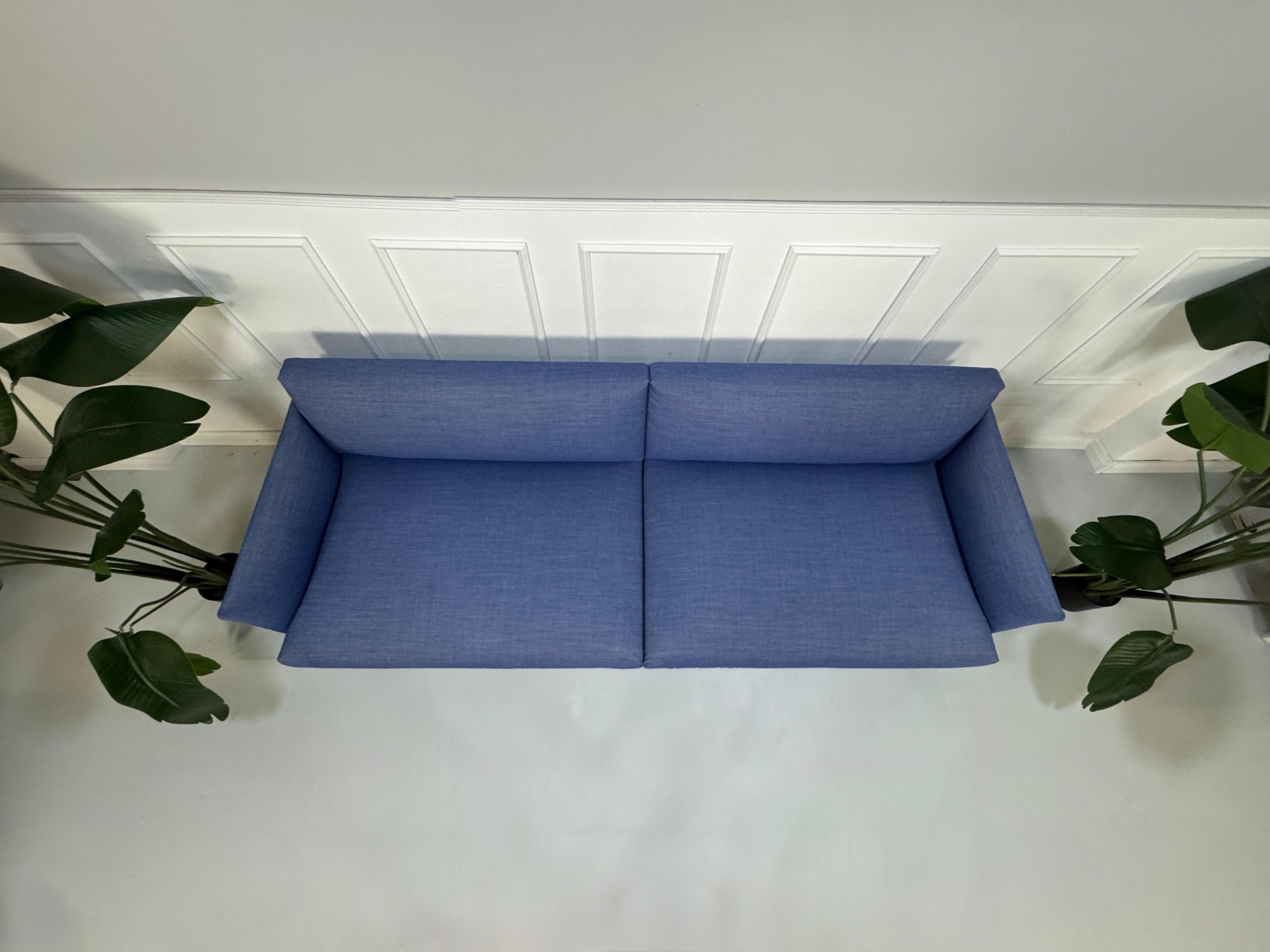 Gebrauchtes blaues Muuto Outline Designer Stoff Sofa vor einer Wand, stilvoll und modern eingerichtet.