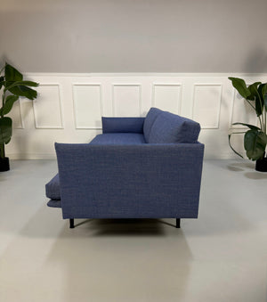 Gebrauchtes blaues Muuto Outline Designer Stoff Sofa vor einer Wand, stilvoll und modern eingerichtet.