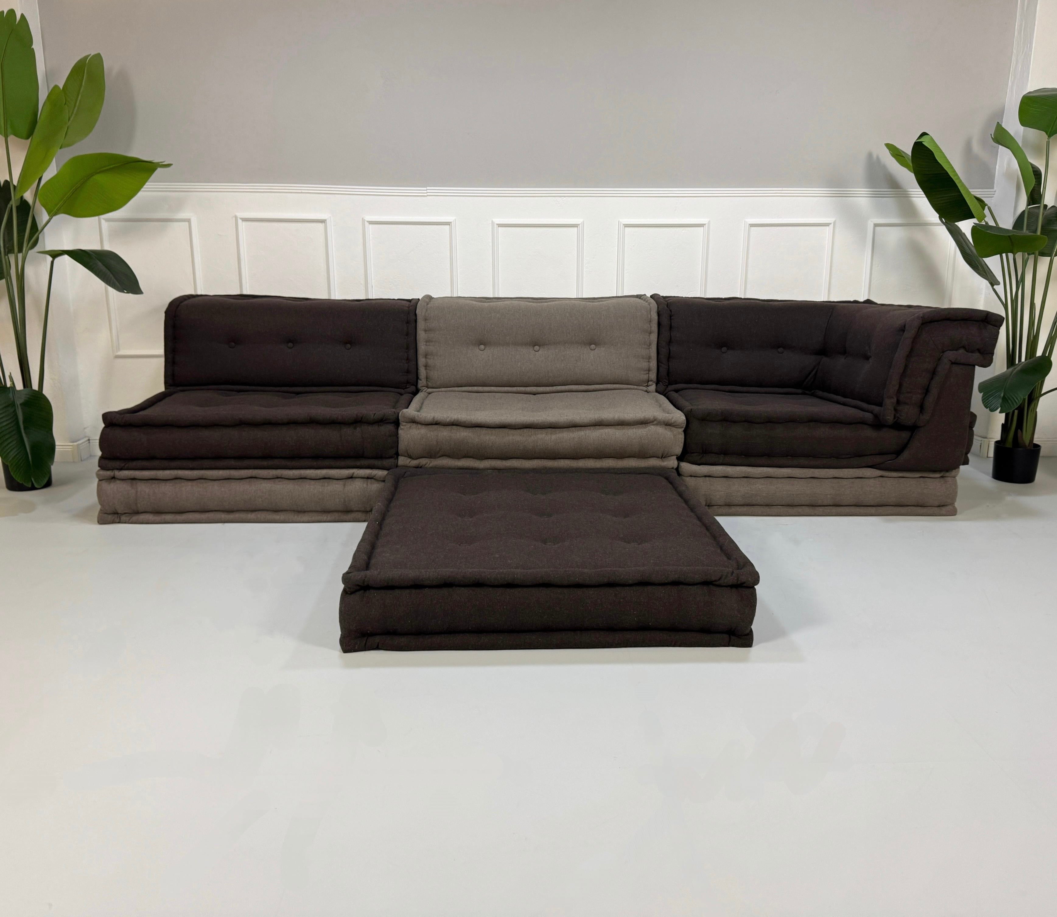 Gebrauchtes Roche Bobois Mah Jong Stoff Sofa in der Farbe Grau vor einer Wand, stilvoll und modern eingerichtet.