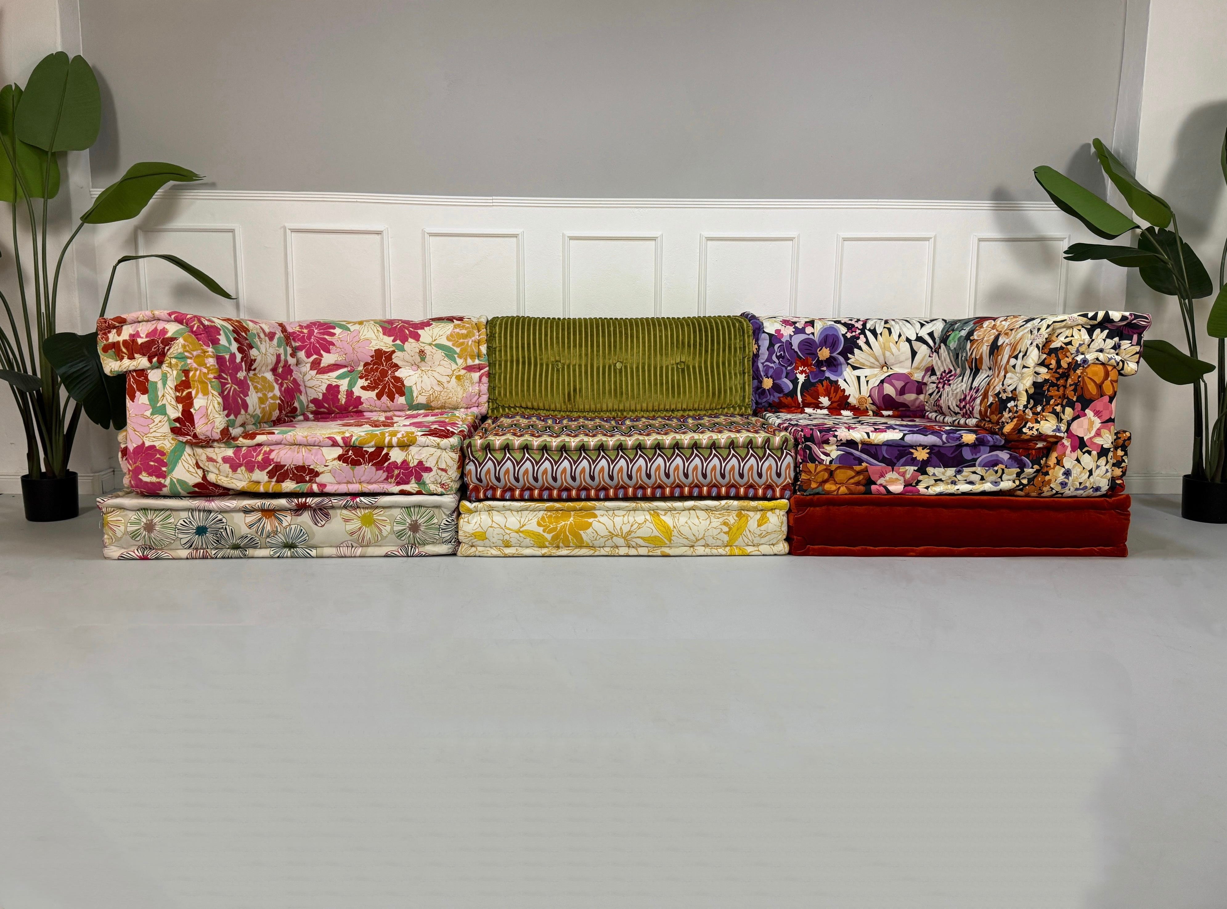 Gebrauchtes buntes Roche Bobois Mah Jong Designer Stoff Sofa vor einer Wand, stilvoll und modern eingerichtet.