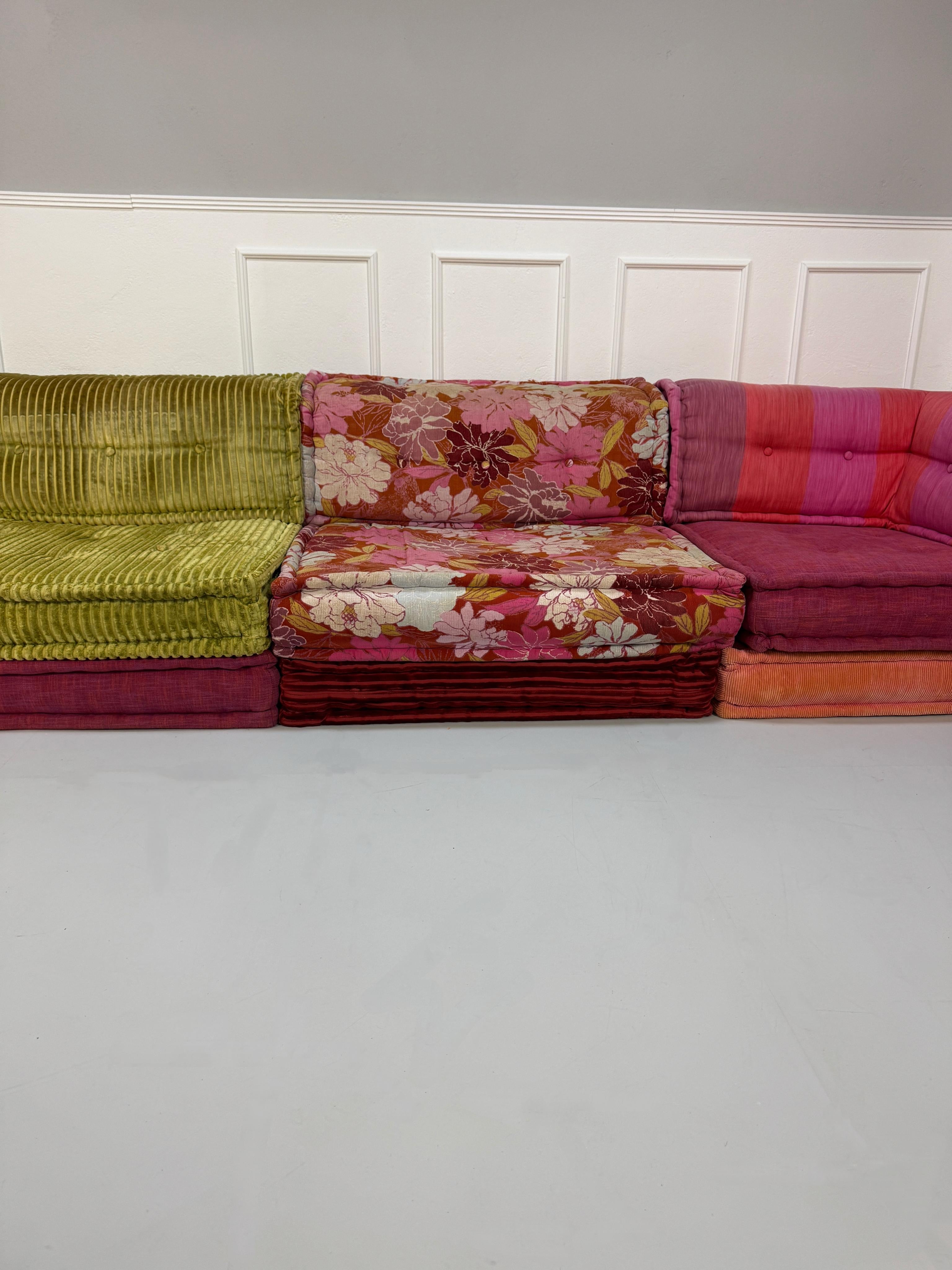 Gebrauchtes buntes Roche Bobois MahJongDesigner Stoff Sofa vor einer Wand, stilvoll und modern eingerichtet.