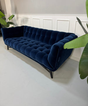 Gebrauchtes  Designer Stoff Sofa vor einer Wand, stilvoll und modern eingerichtet.