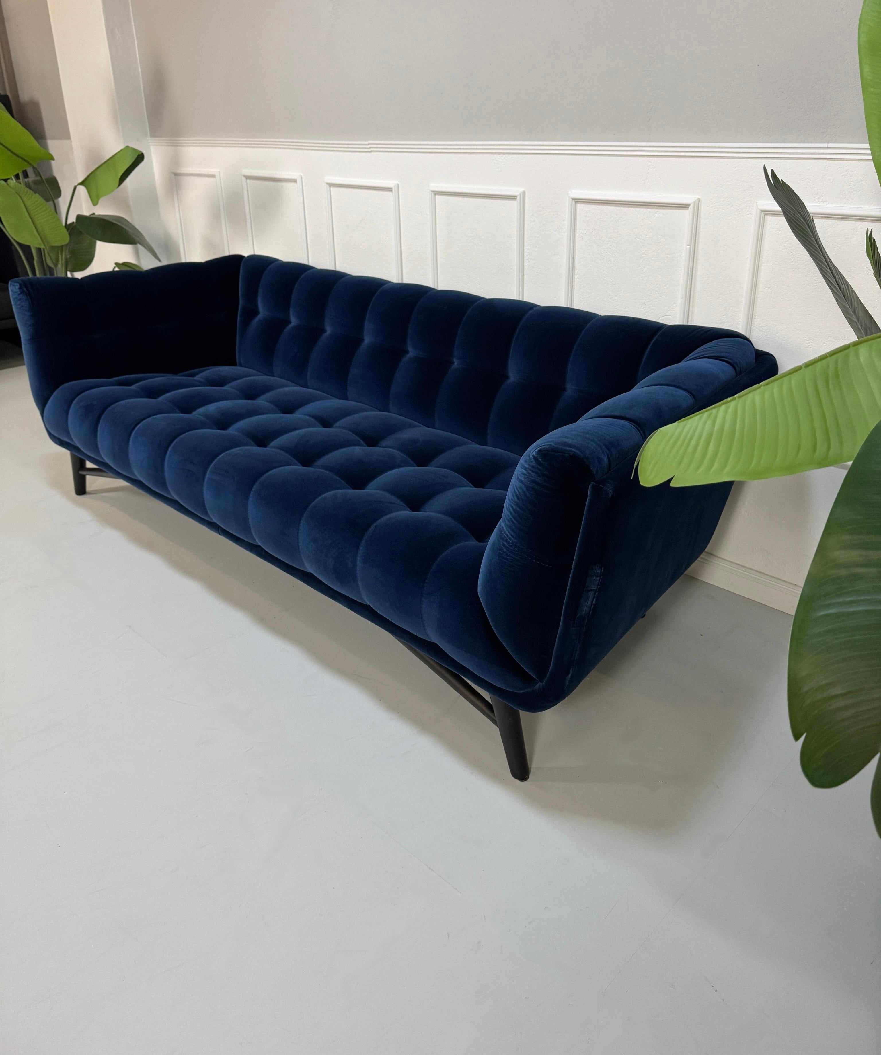 Gebrauchtes  Designer Stoff Sofa vor einer Wand, stilvoll und modern eingerichtet.