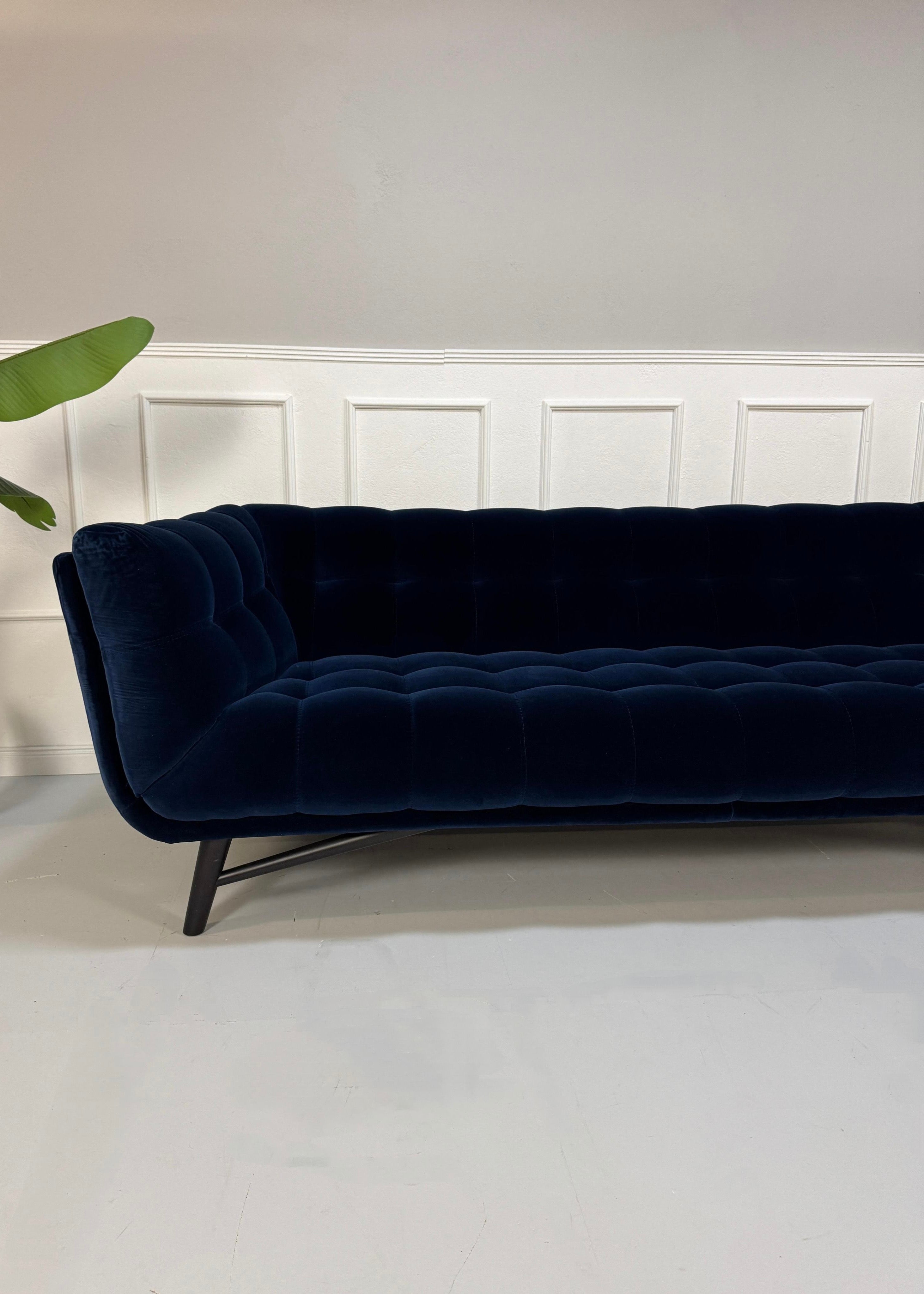 Gebrauchtes  Designer Stoff Sofa vor einer Wand, stilvoll und modern eingerichtet.