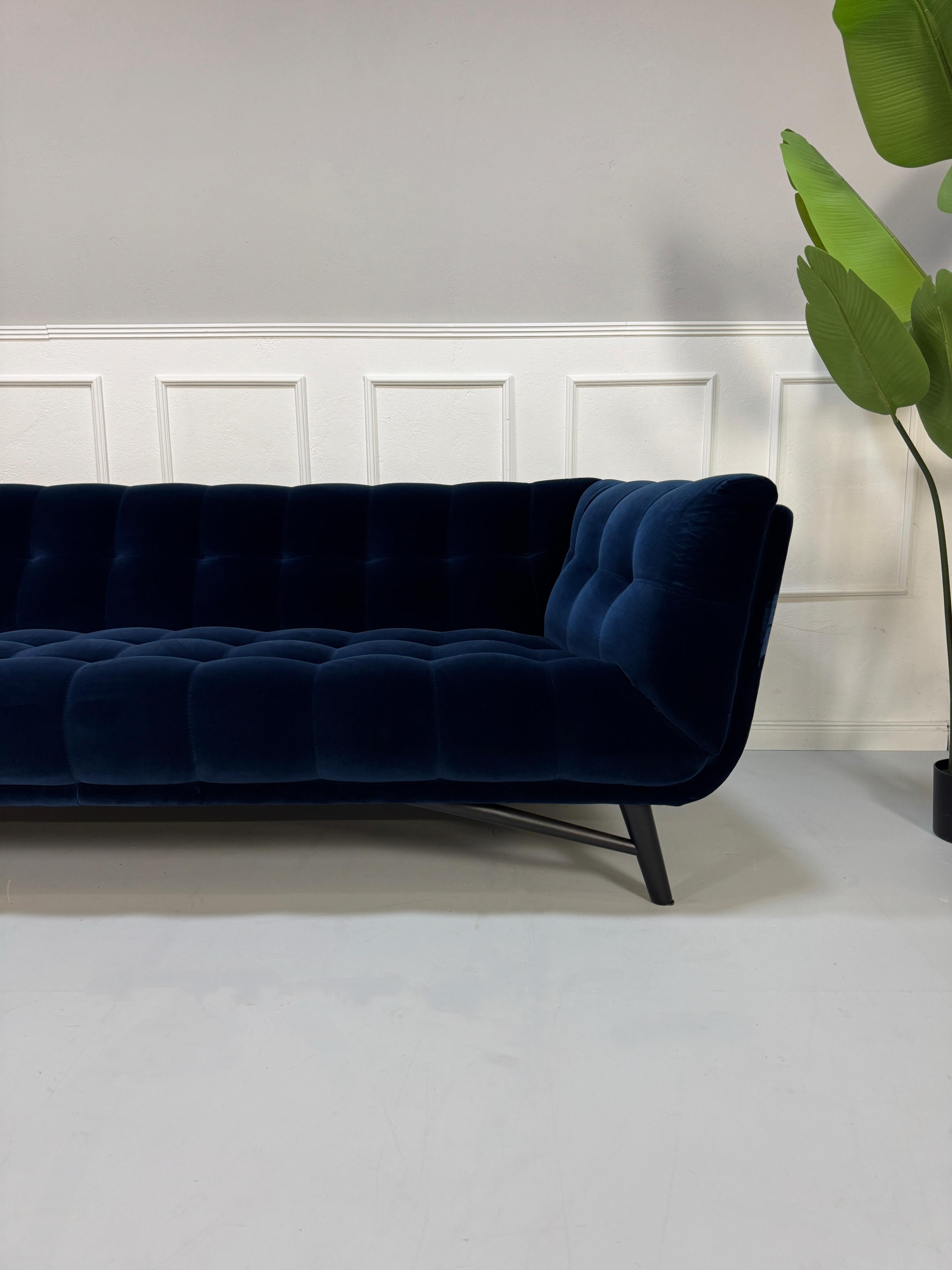 Gebrauchtes  Designer Stoff Sofa vor einer Wand, stilvoll und modern eingerichtet.