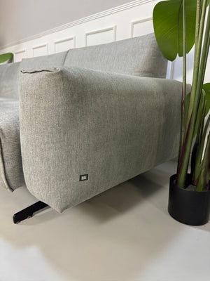 Gebrauchtes graues Rolf Benz 50 Designer Stoff Sofa vor einer Wand, stilvoll und modern eingerichtet.