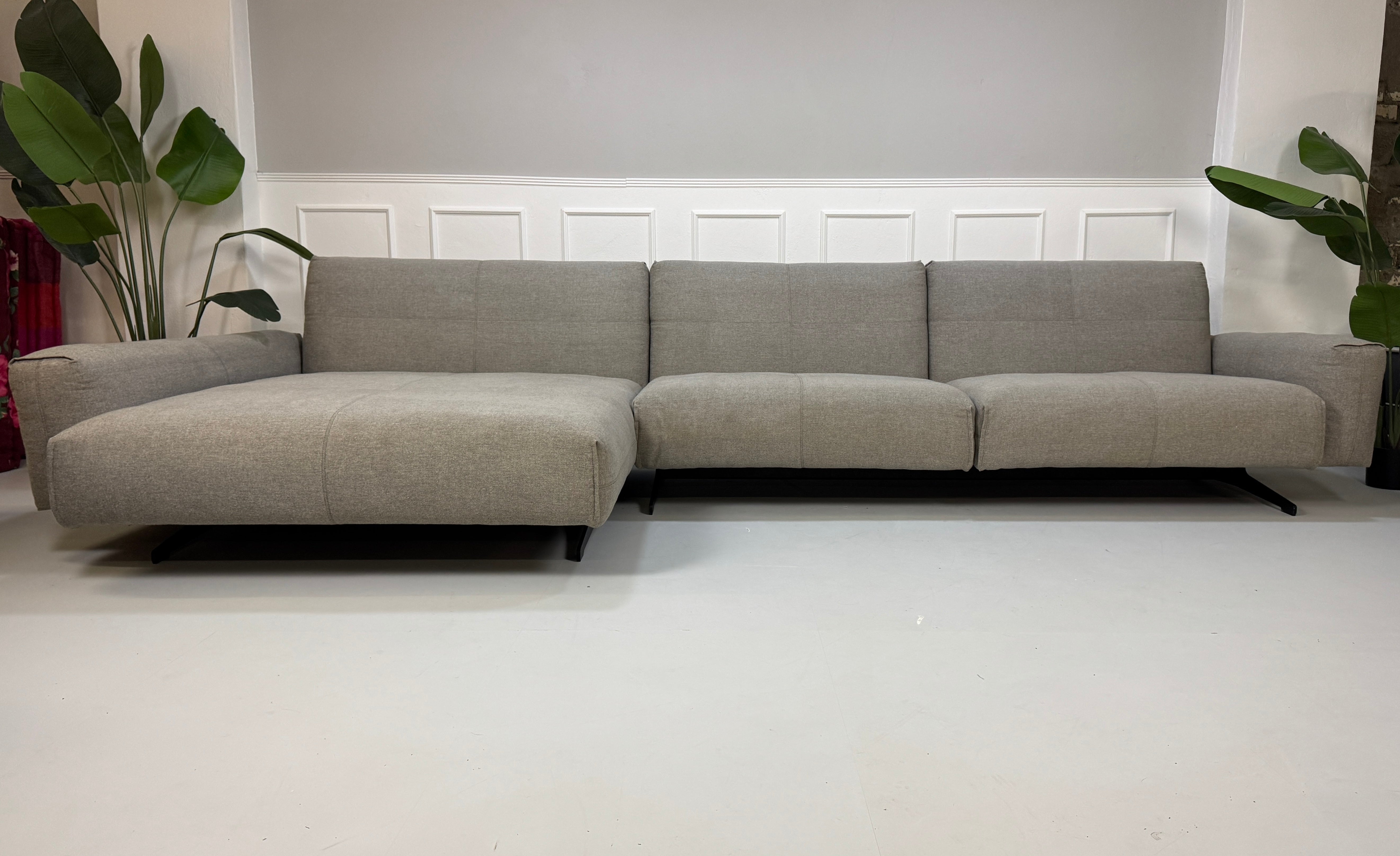 Gebrauchtes Rolf Benz 50 Stoff Ecksofa in der Farbe Grau vor einer Wand, stilvoll und modern eingerichtet.