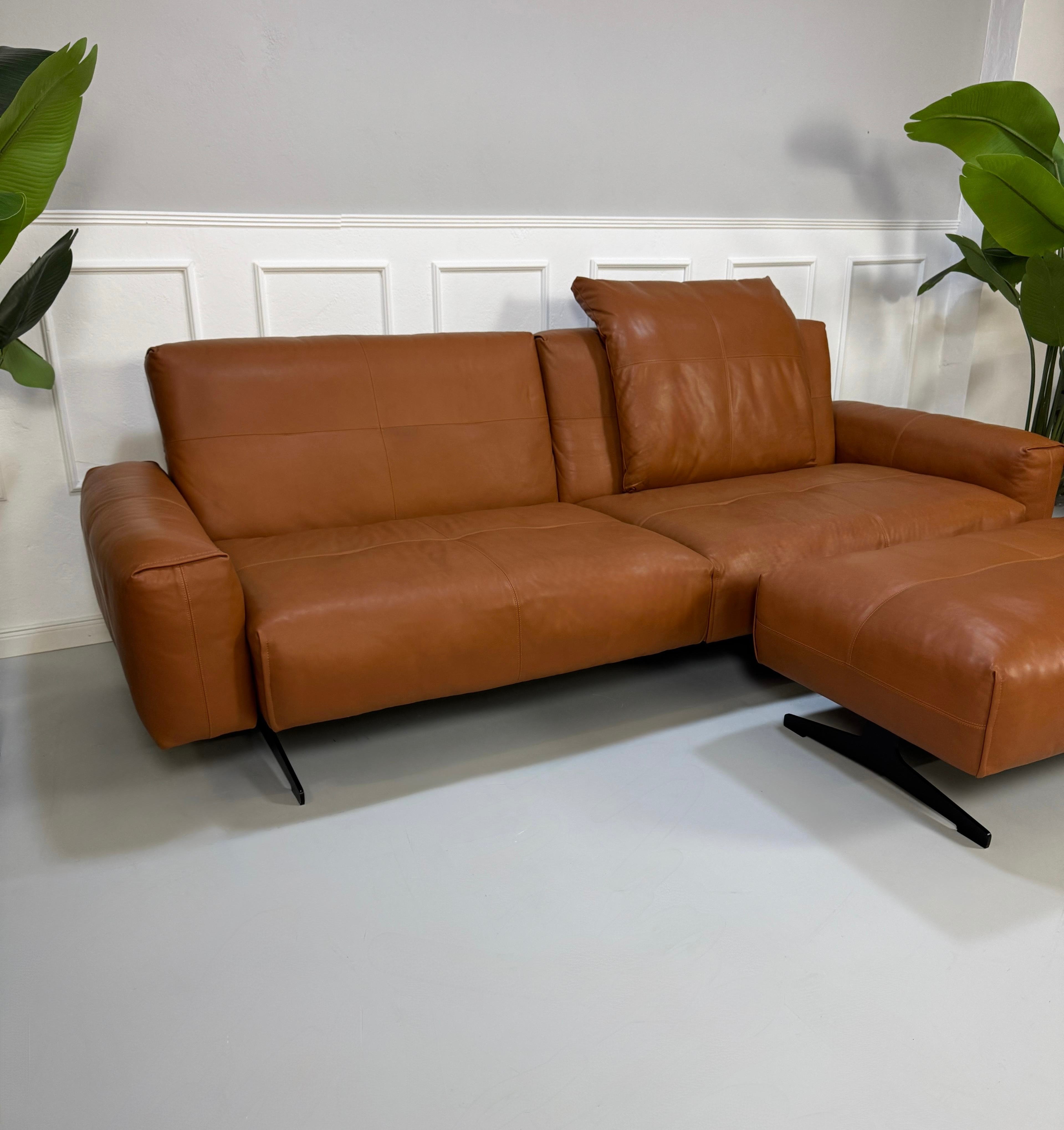 Gebrauchte braune Rolf Benz Leder 50 Designer Leder Garnitur vor einer Wand, stilvoll und modern eingerichtet.