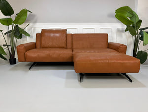 Gebrauchte braune Rolf Benz Leder 50 Designer Leder Garnitur vor einer Wand, stilvoll und modern eingerichtet.