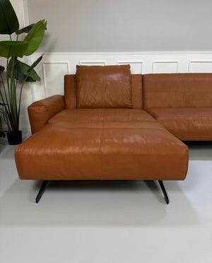 Gebrauchte braune Rolf Benz Leder 50 Designer Leder Garnitur vor einer Wand, stilvoll und modern eingerichtet.
