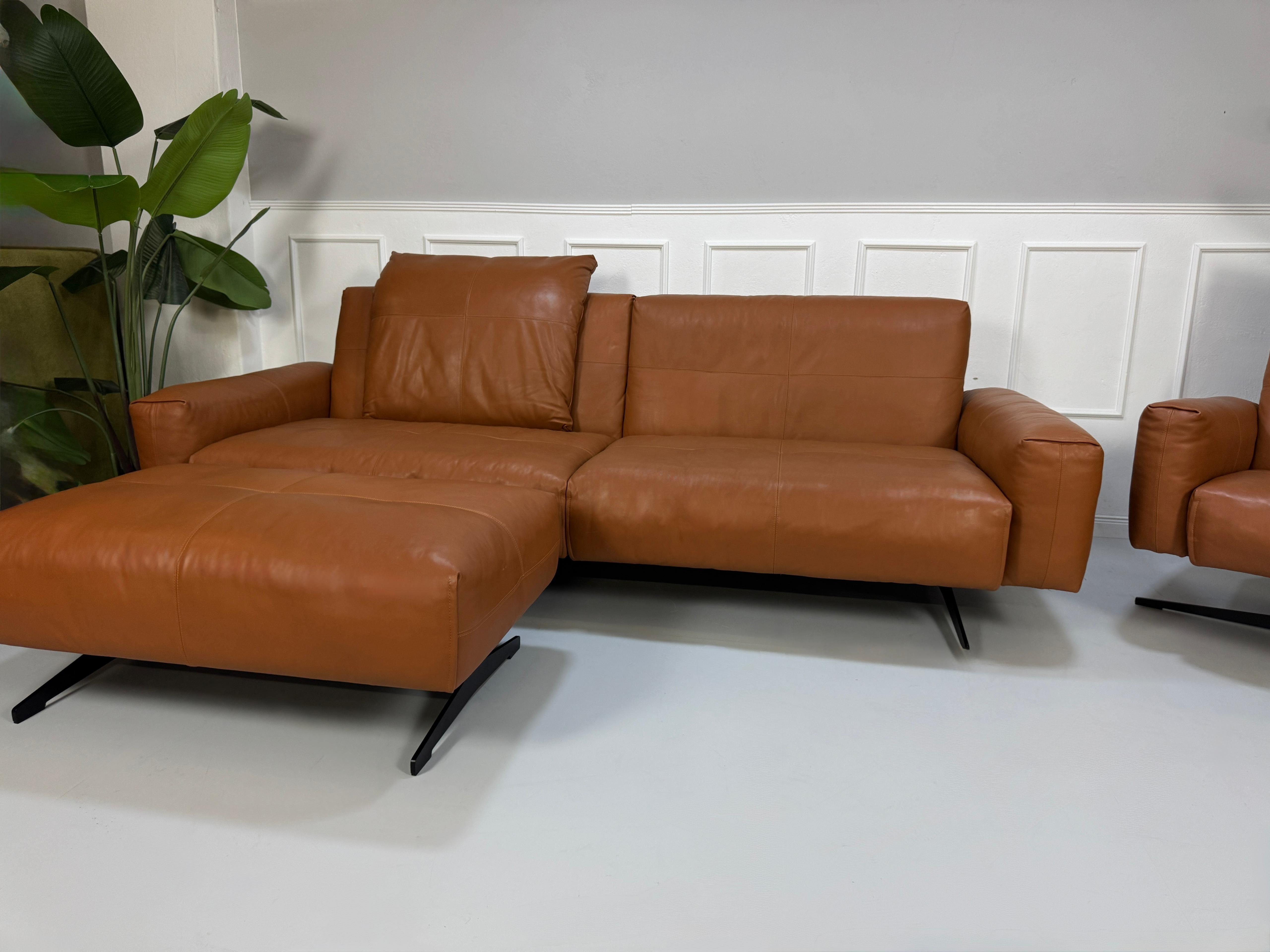 Gebrauchte braune Rolf Benz Leder 50 Designer Leder Garnitur vor einer Wand, stilvoll und modern eingerichtet.