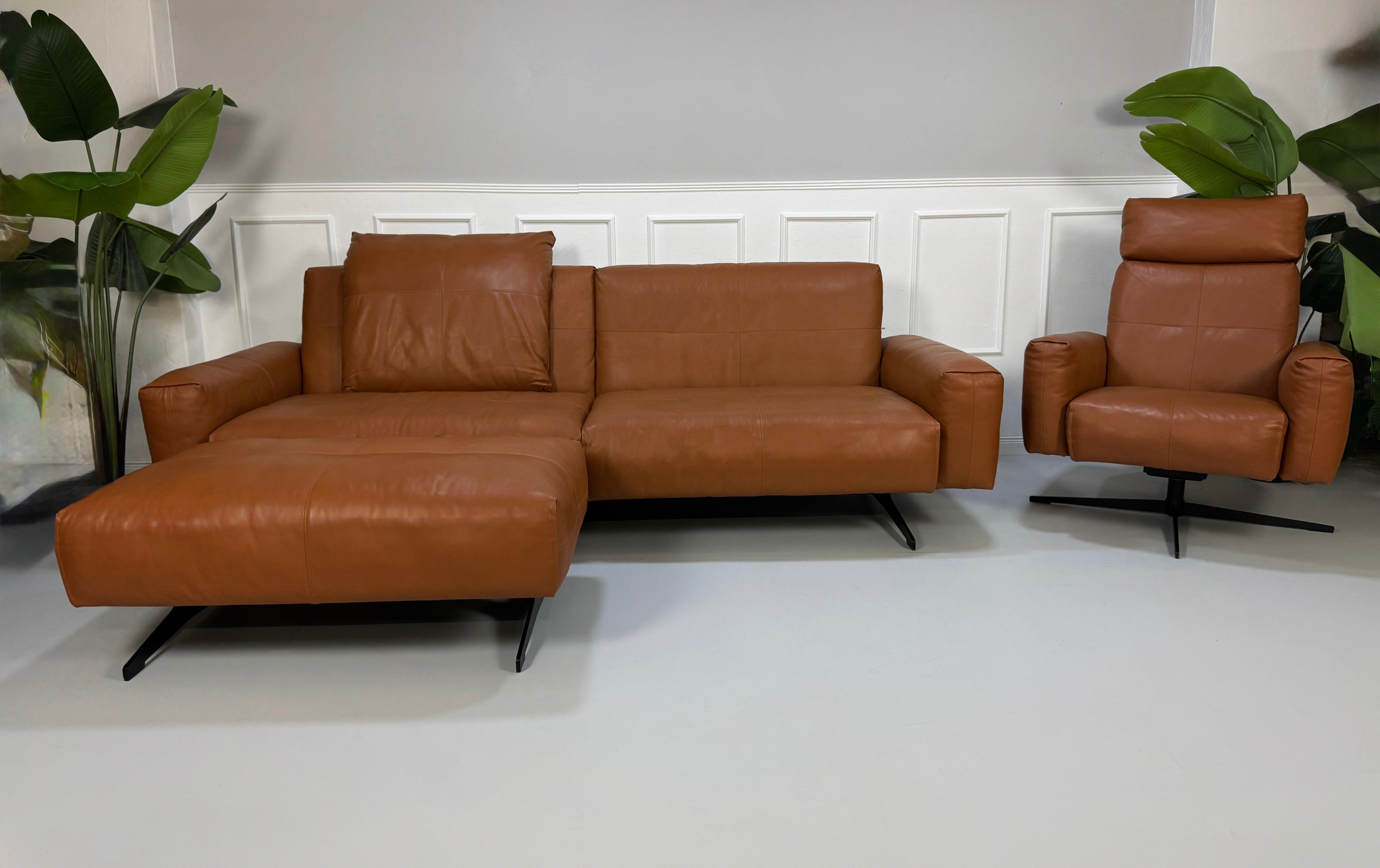 Gebrauchte braune Rolf Benz Leder 50 Designer Leder Garnitur vor einer Wand, stilvoll und modern eingerichtet.