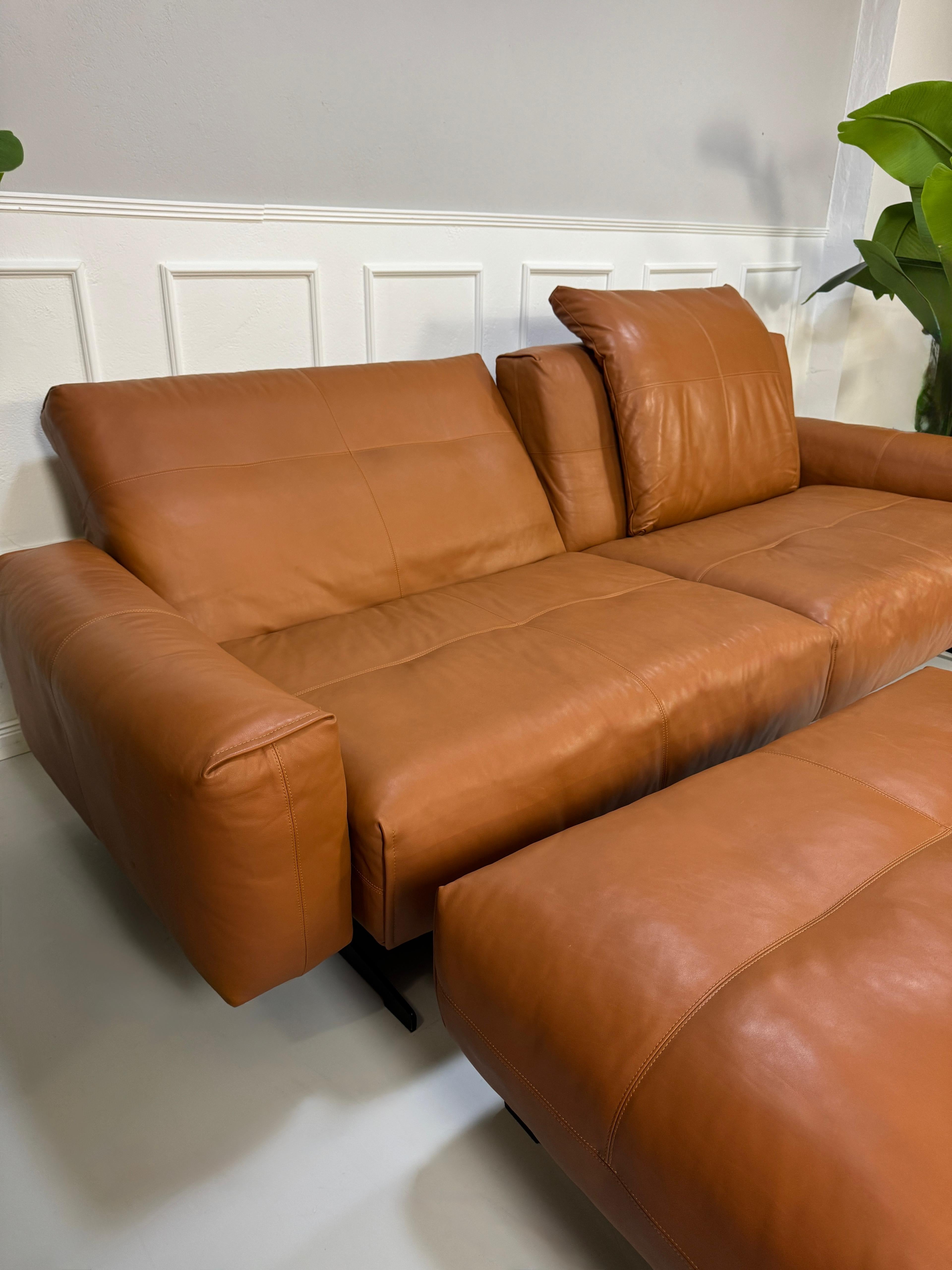 Gebrauchte braune Rolf Benz Leder 50 Designer Leder Garnitur vor einer Wand, stilvoll und modern eingerichtet.