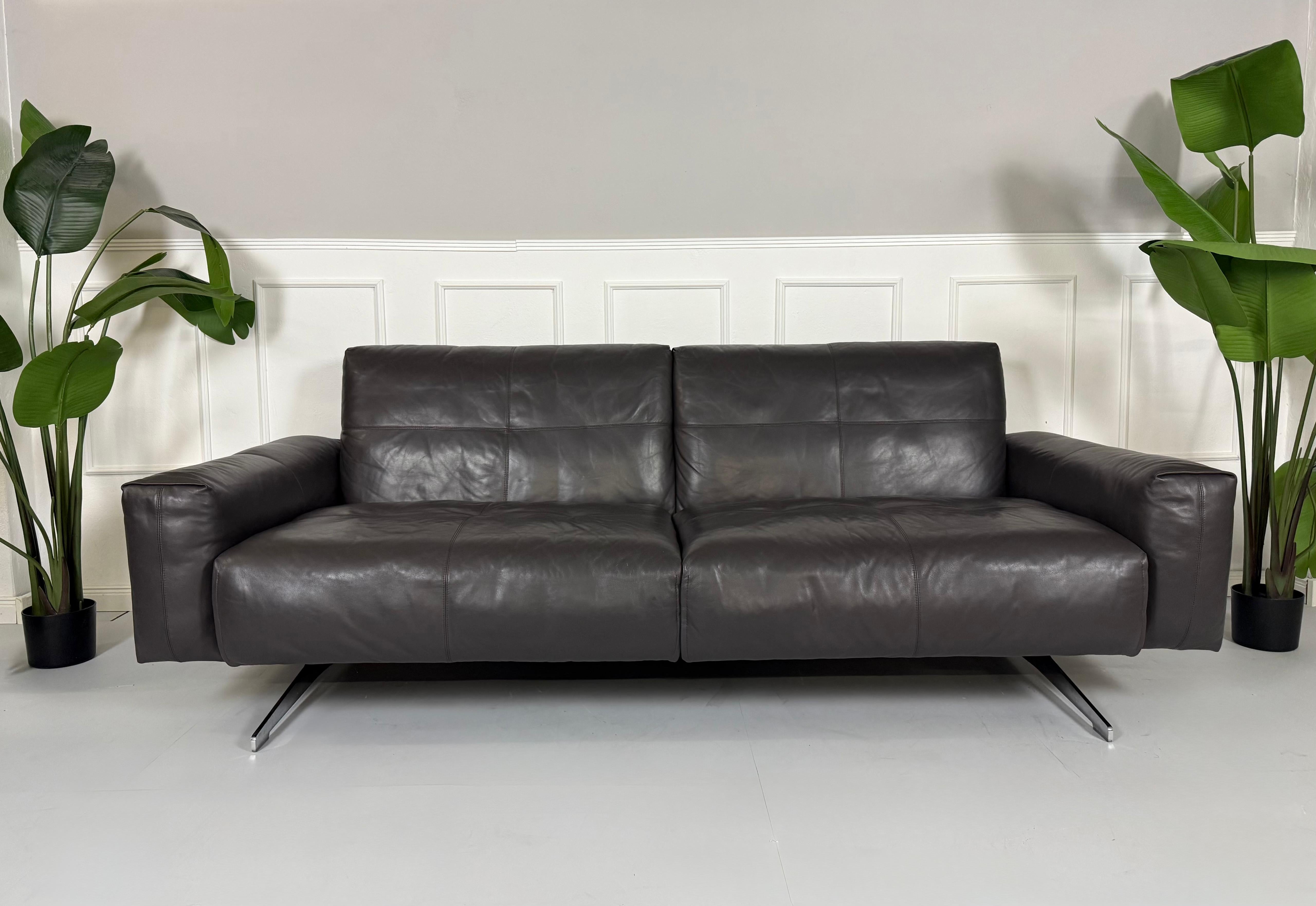 Refurbished graues Rolf Benz 50  Designer Leder Sofa vor einer Wand, stilvoll und modern eingerichtet.