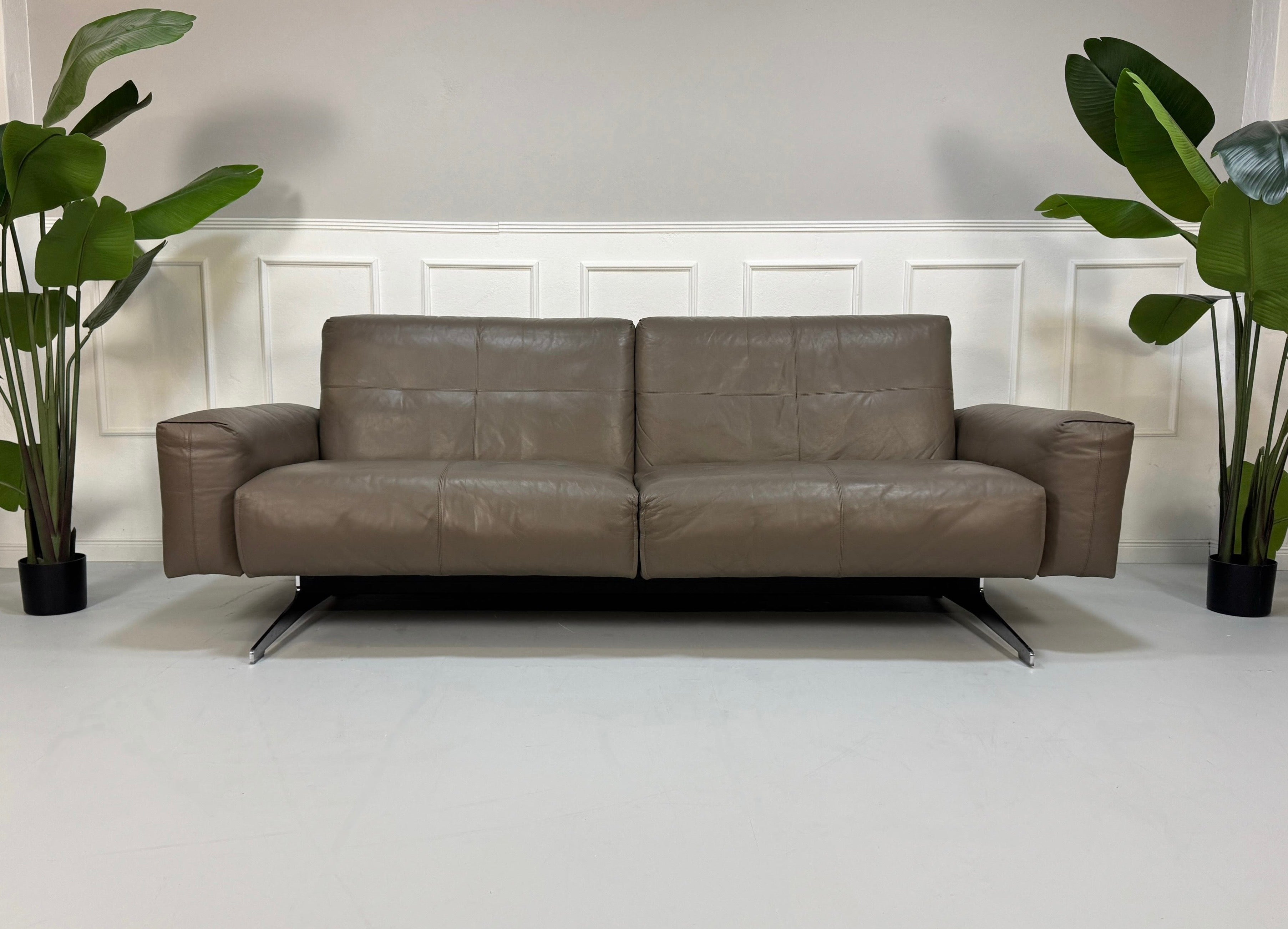 Gebrauchtes grau braunes Rolf Benz 50 Designer Leder Sofa vor einer Wand, stilvoll und modern eingerichtet.