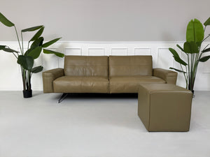 Erneuertes Rolf Benz 50 mit Hocker  Designer Leder Sofa vor einer Wand, stilvoll und modern eingerichtet.