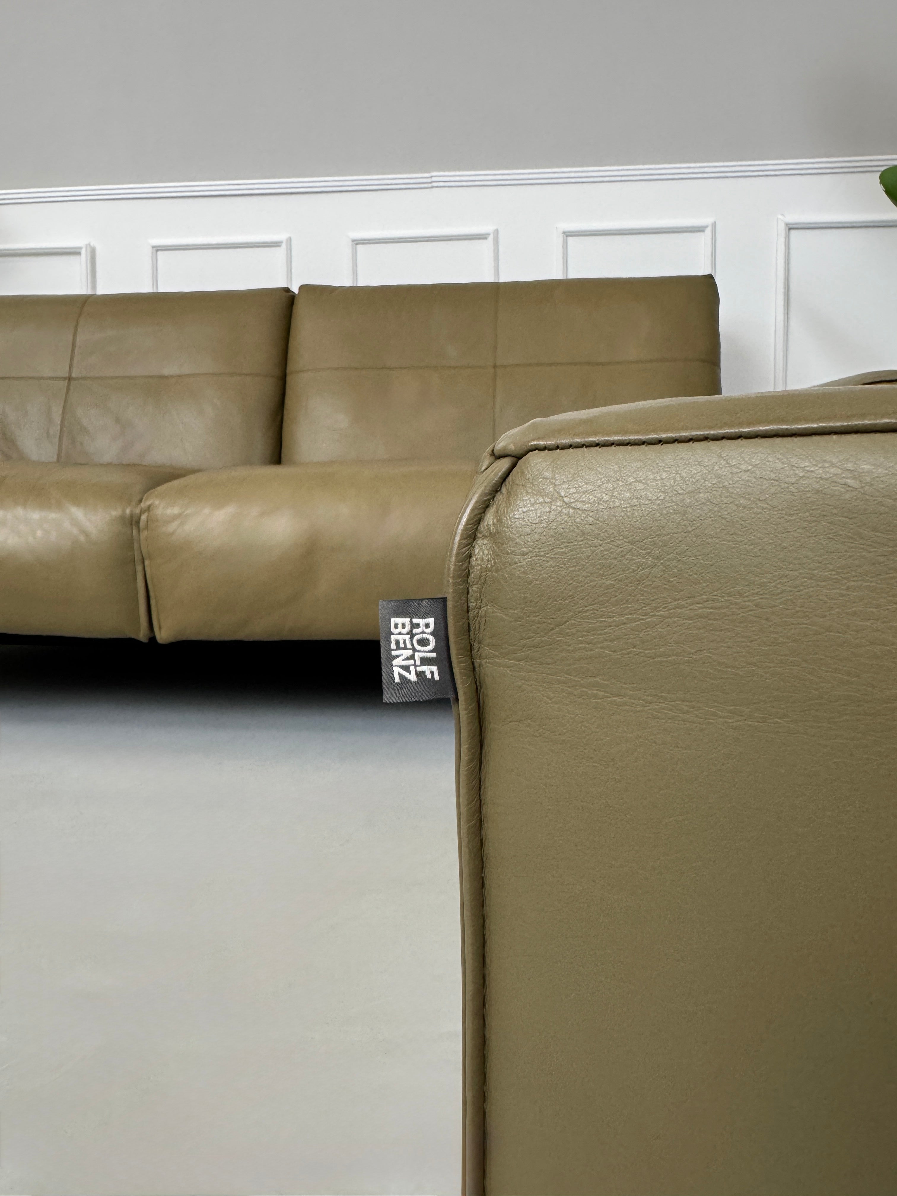 Erneuertes Rolf Benz 50 mit Hocker  Designer Leder Sofa vor einer Wand, stilvoll und modern eingerichtet.