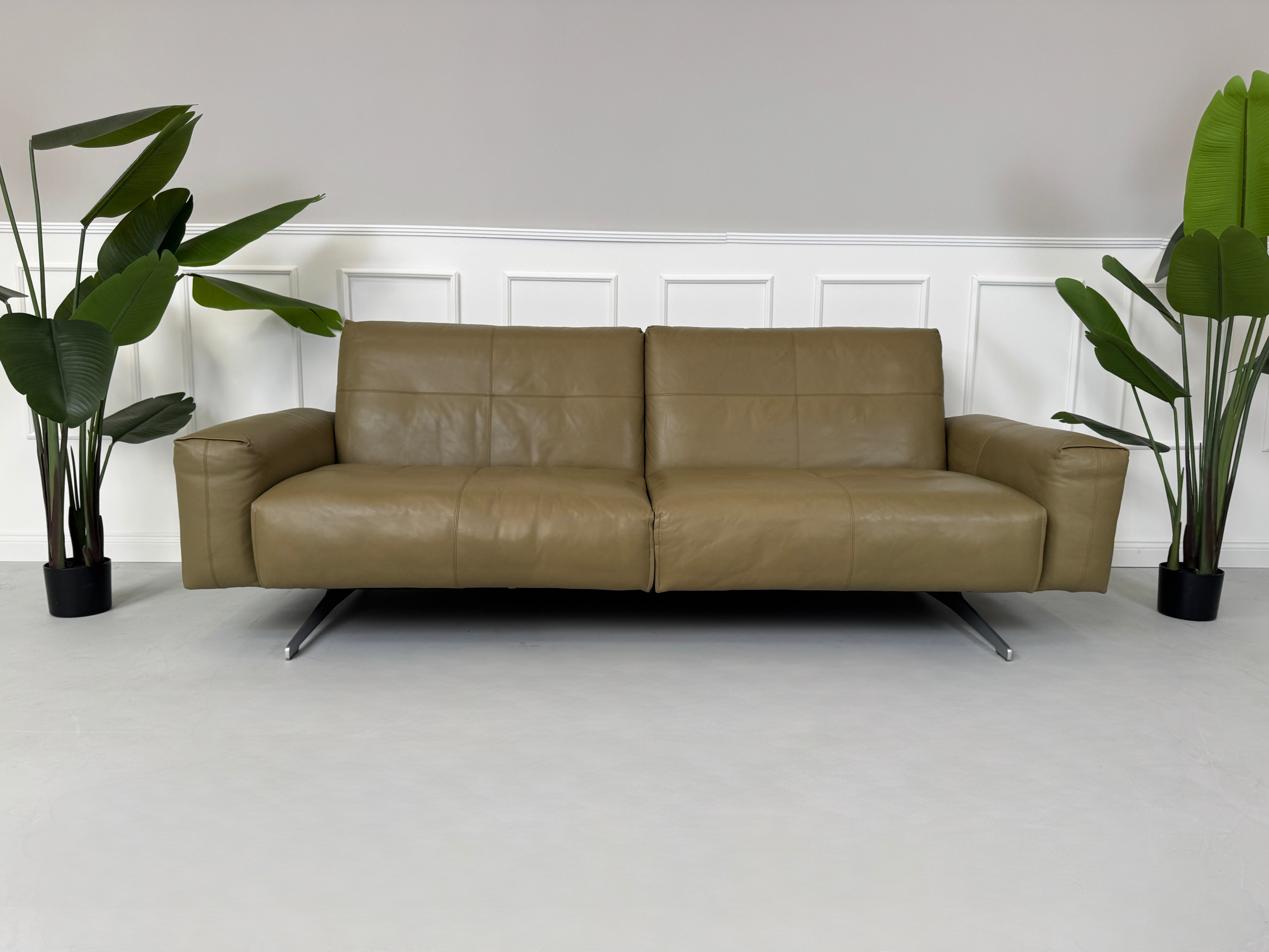 Erneuertes Rolf Benz 50 mit Hocker  Designer Leder Sofa vor einer Wand, stilvoll und modern eingerichtet.
