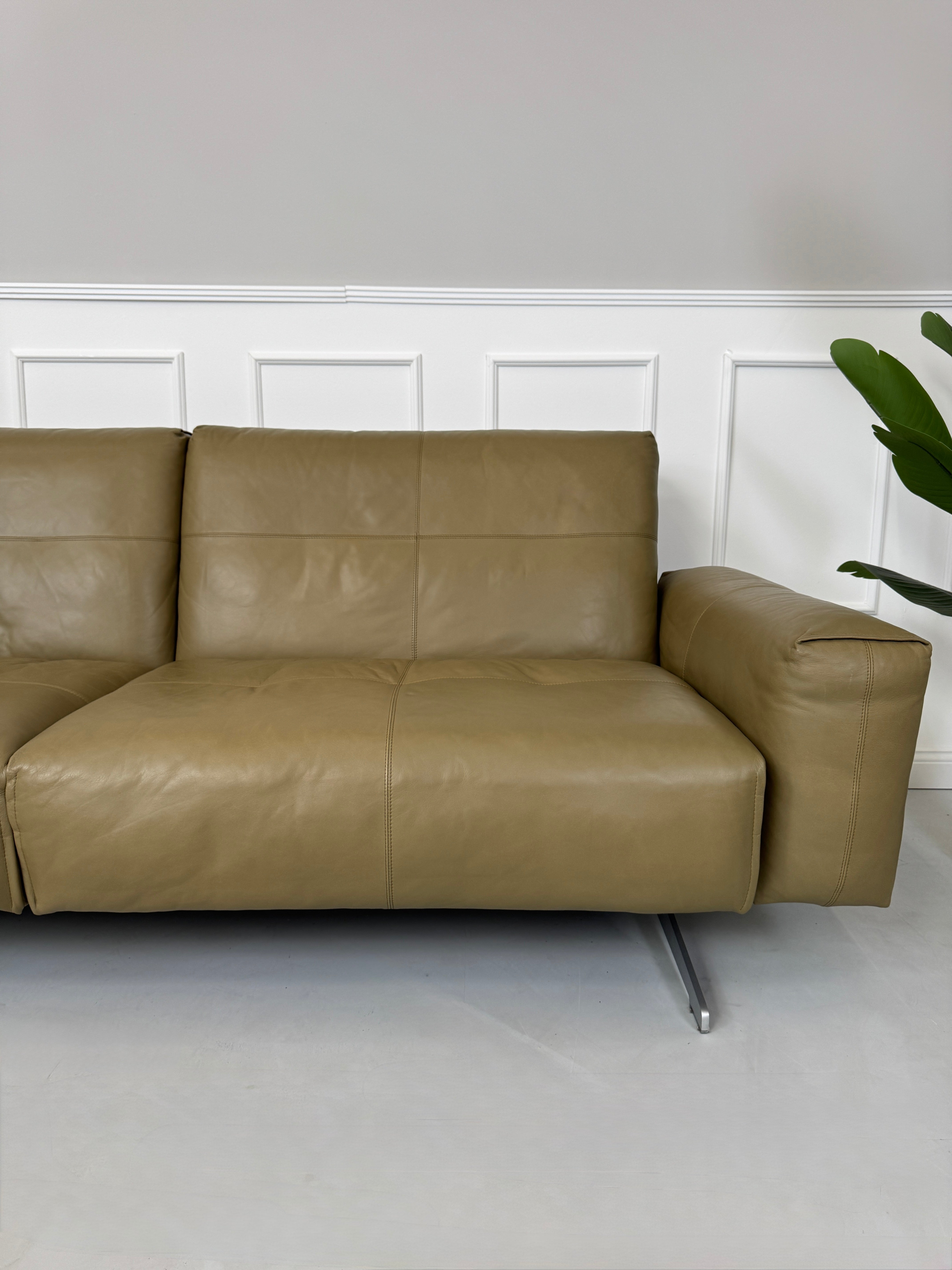 Erneuertes Rolf Benz 50 mit Hocker  Designer Leder Sofa vor einer Wand, stilvoll und modern eingerichtet.