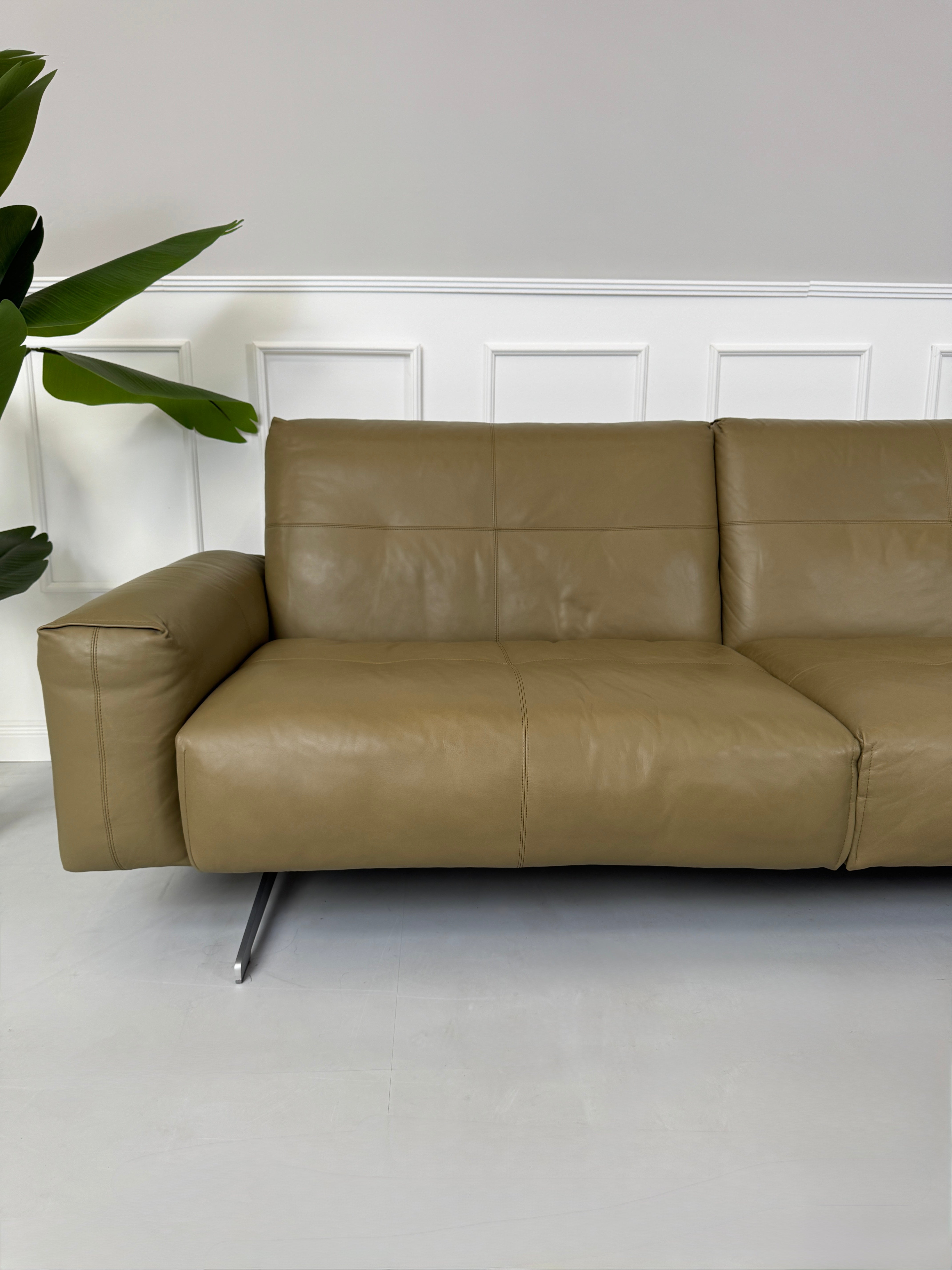 Erneuertes Rolf Benz 50 mit Hocker  Designer Leder Sofa vor einer Wand, stilvoll und modern eingerichtet.