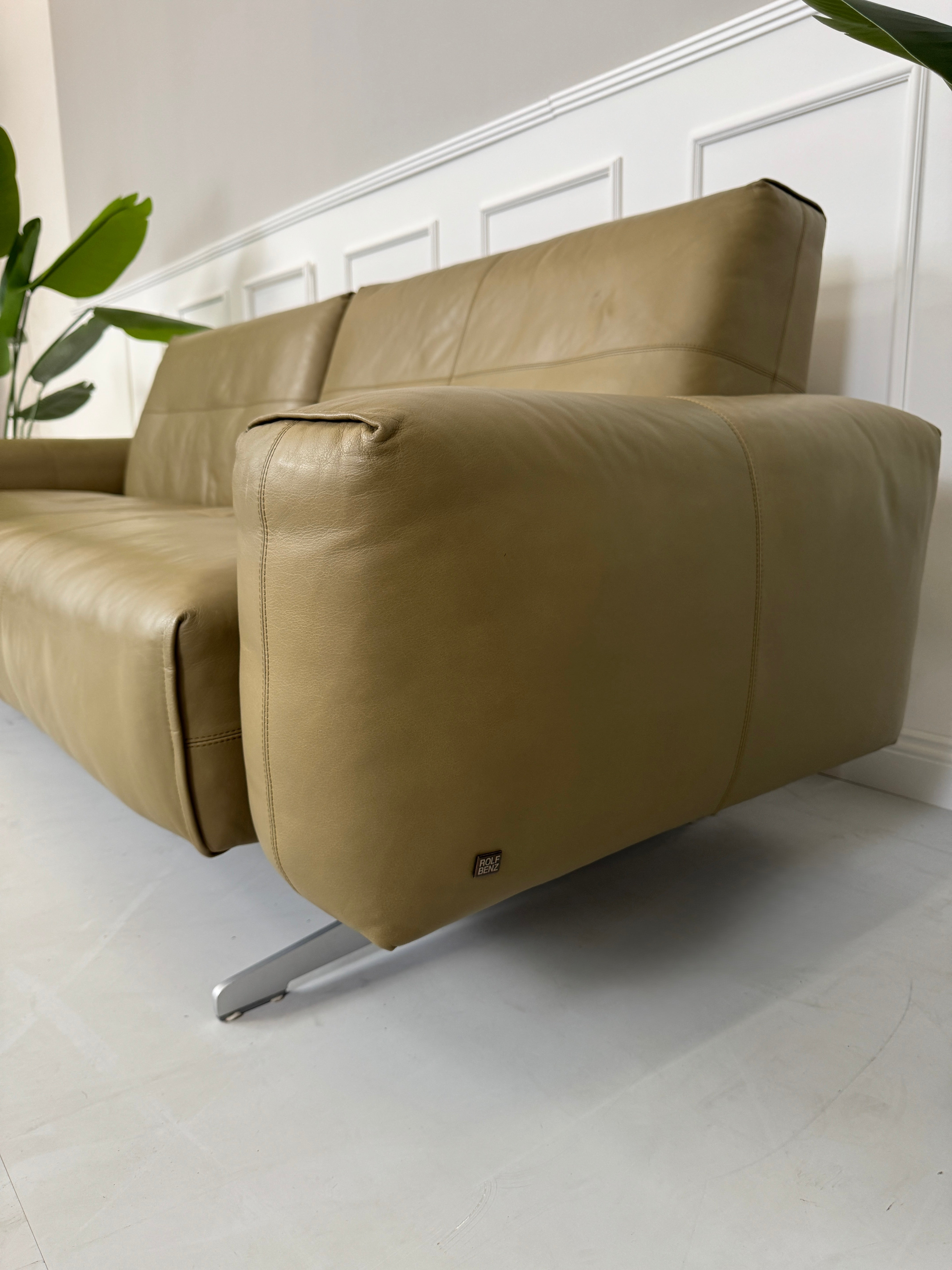 Erneuertes Rolf Benz 50 mit Hocker  Designer Leder Sofa vor einer Wand, stilvoll und modern eingerichtet.