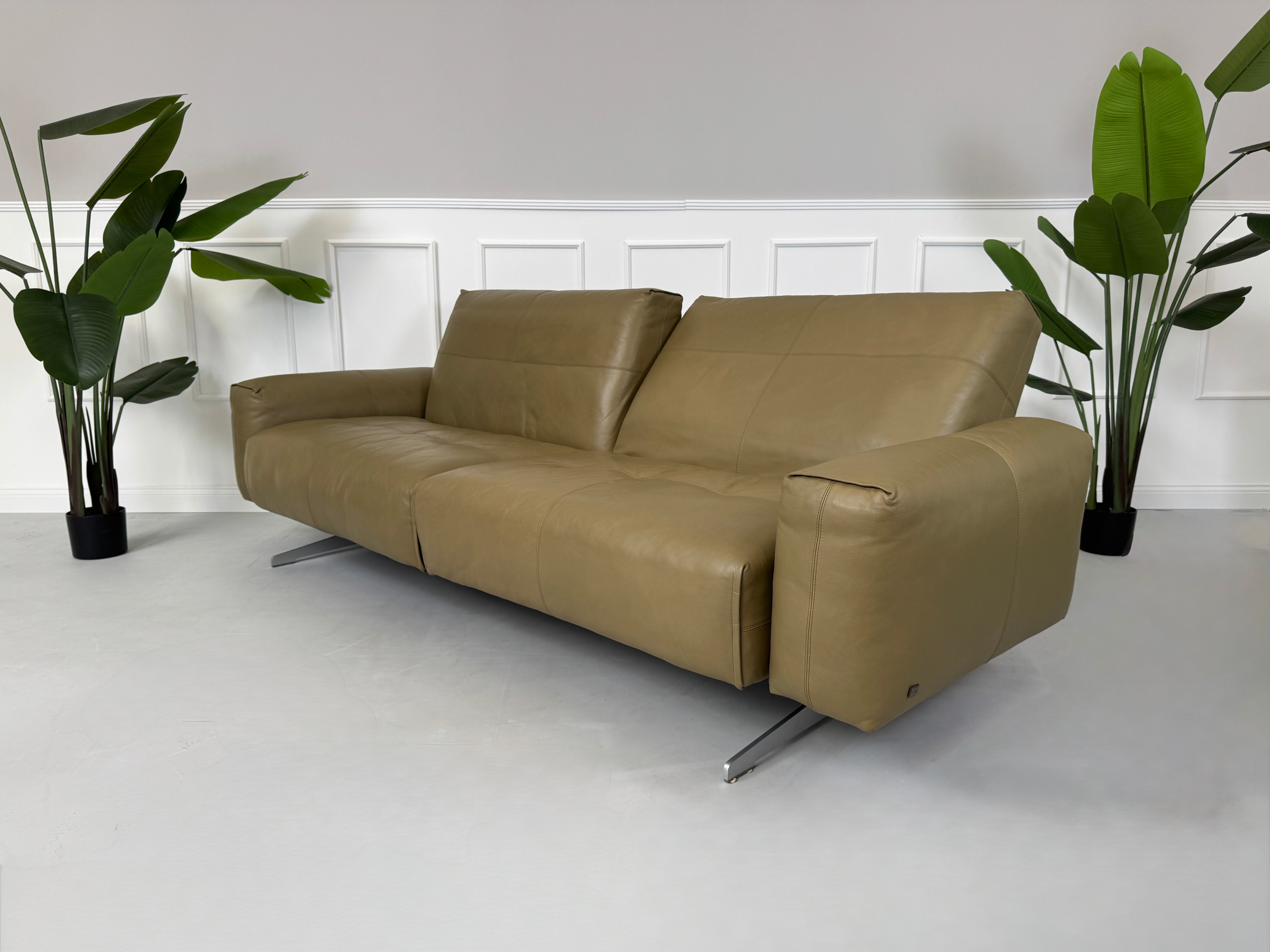 Erneuertes Rolf Benz 50 mit Hocker  Designer Leder Sofa vor einer Wand, stilvoll und modern eingerichtet.
