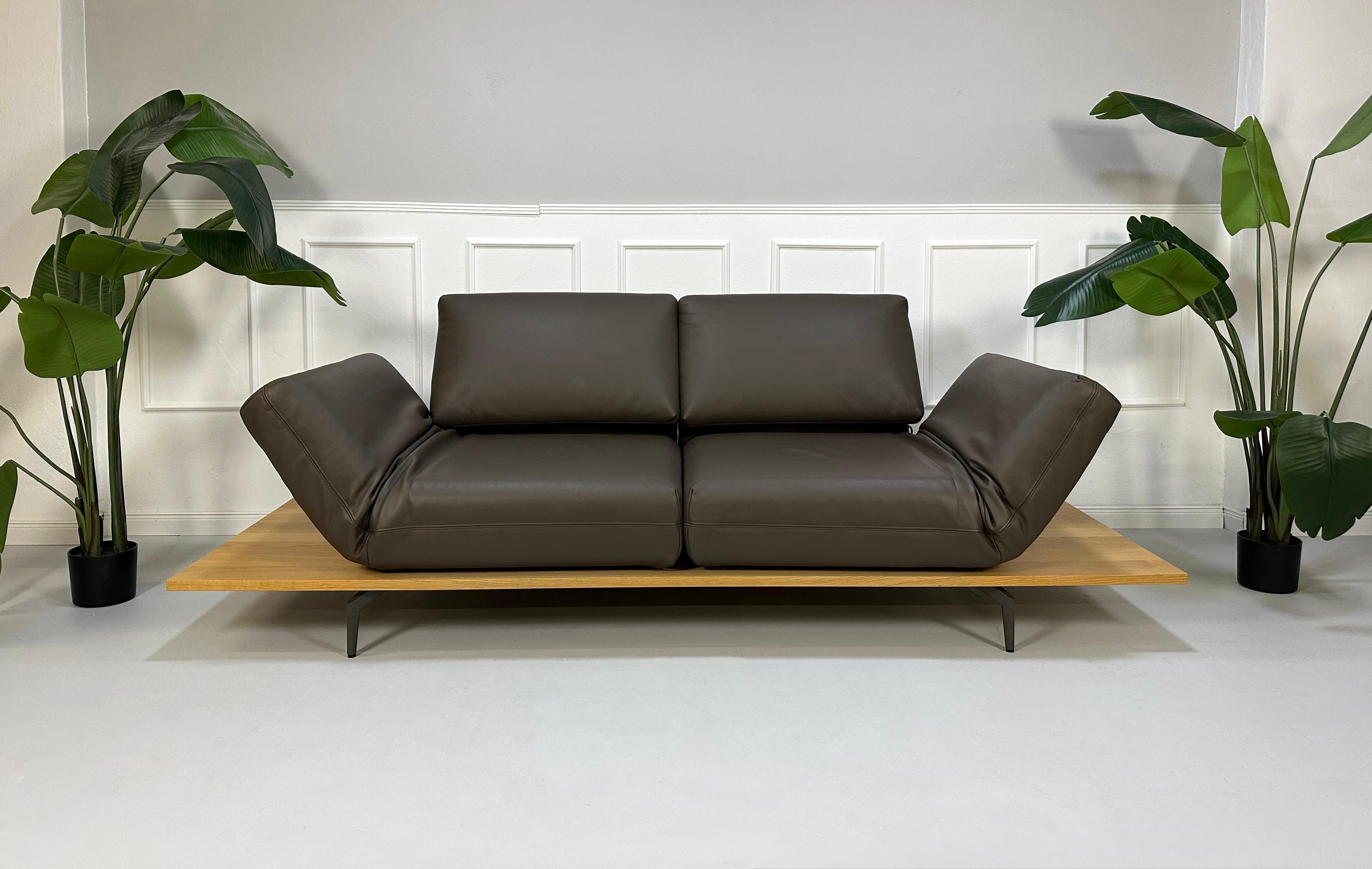 Gebrauchtes braunes Rolf Benz Aura Designer Leder Sofa vor einer Wand, stilvoll und modern eingerichtet.