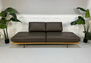 Gebrauchtes braunes Rolf Benz Aura Designer Leder Sofa vor einer Wand, stilvoll und modern eingerichtet.